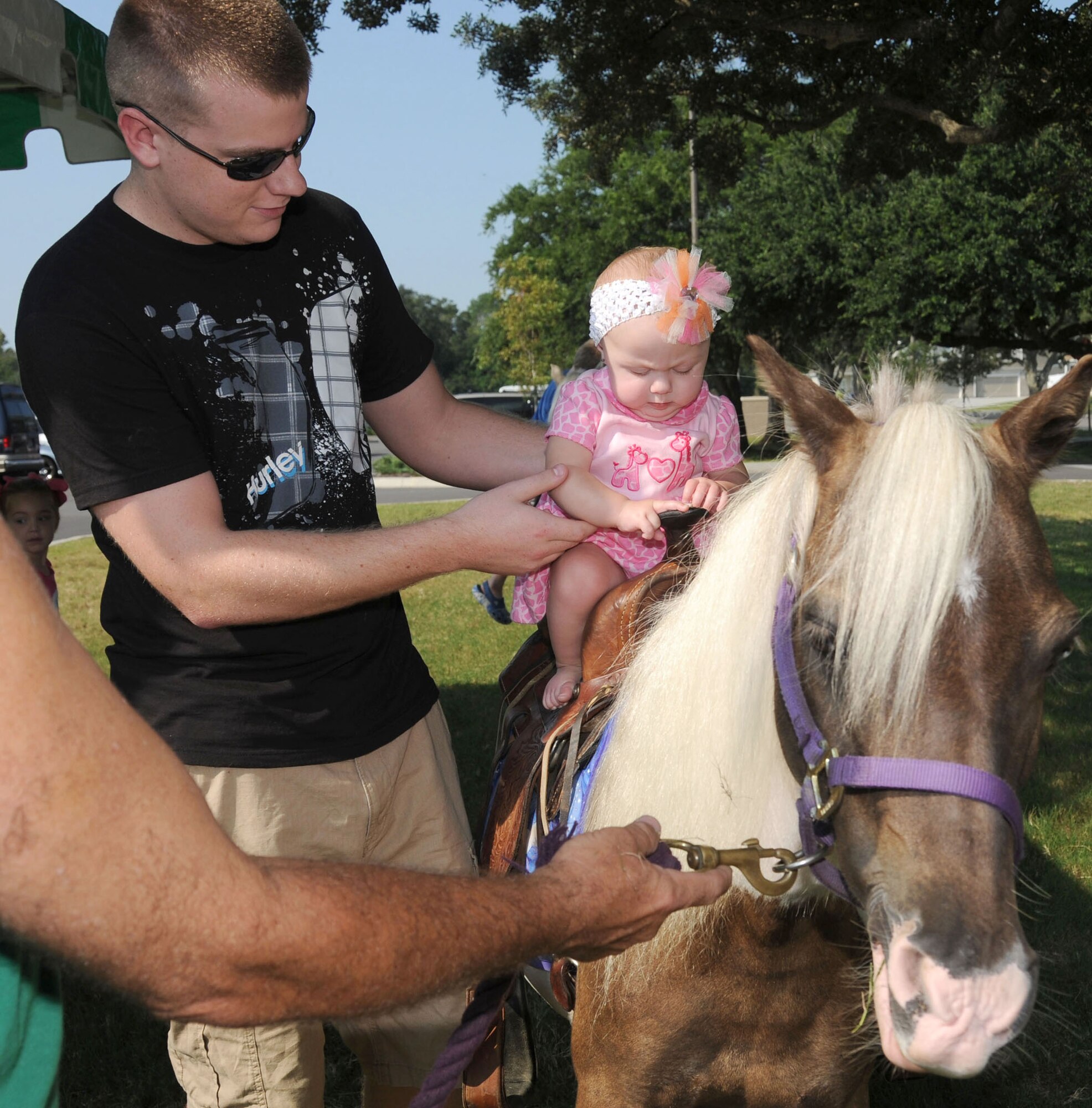 Airman 1st Class Jason Lillis, 81st Logistics Readiness Squadron, puts his 8-month-old daughter Kaylee on top of a pony, Shy-Anne, for a ride during the Keesler 70th Birthday Celebration at Bay Breeze Event Center Aug. 27.  (U.S. Air Force photo by Kemberly Groue)