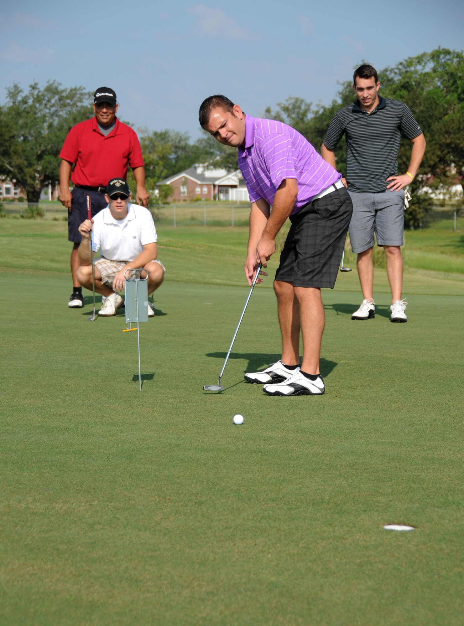 Left, Major Nieves Villasenor, Marine Detachment Commanding Office; kneeling, Sgt Chad Radich, MARDET; and far right, Aaron Lamey of Biloxi, watch closely at Les Valentine of Biloxi attempts to make a birdie putt on hole #10 during the Keesler 70th Birthday Celebration Golf Tournament Aug. 27.  (U.S. Air Force photo by Kemberly Groue)
