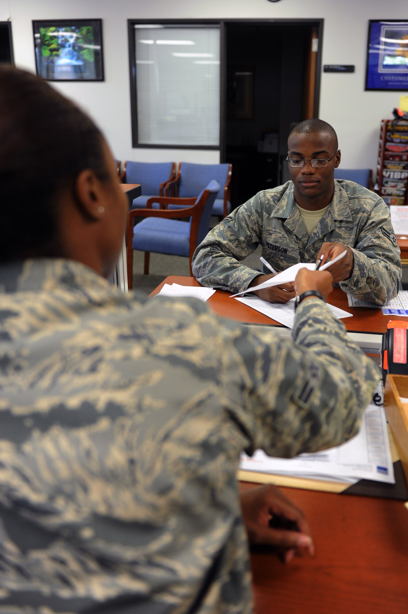Airman 1st Class Brent Peterson, a 373rd Training Squadron trainee receives an application for shipment/storage of personal property from Airman 1st Class De’Andra Simmons, a 19th Logistics Readiness Squadron traffic management apprentice Aug. 29, 2011, at Little Rock Air Force Base, Ark. The TMO office is located in room 104 in building 1255. Office hours are 8 a.m. to 4 p.m. The office is closed on Thursdays for training from 8 a.m. to 9 a.m. (U.S. Air Force photo by Airman 1st Class Rusty Frank) 