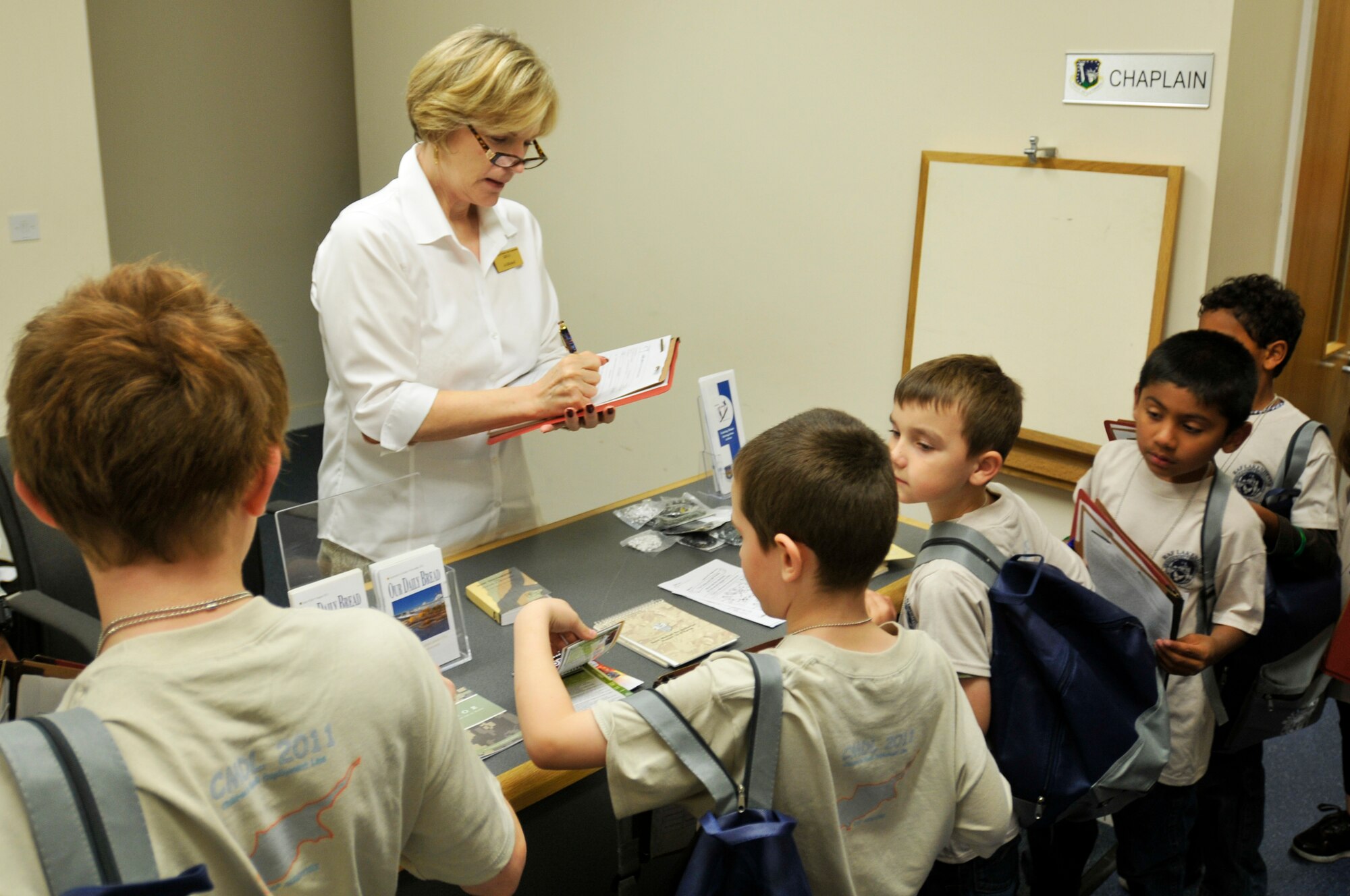 ROYAL AIR FORCE LAKENHEATH, England - Jo Mitchell, 48th Force Support Squadron Military and Family Life consultant, signs a deployment line checklist as children process through the line at the Installation Deployment Readiness Center for a simulated deployment line, Aug. 25, 2011. The mock deployment line is designed to provide children with a better understanding of what their parents experience as they prepare for deployment. (U.S. Air Force photo/Senior Airman Tiffany M. Deuel)