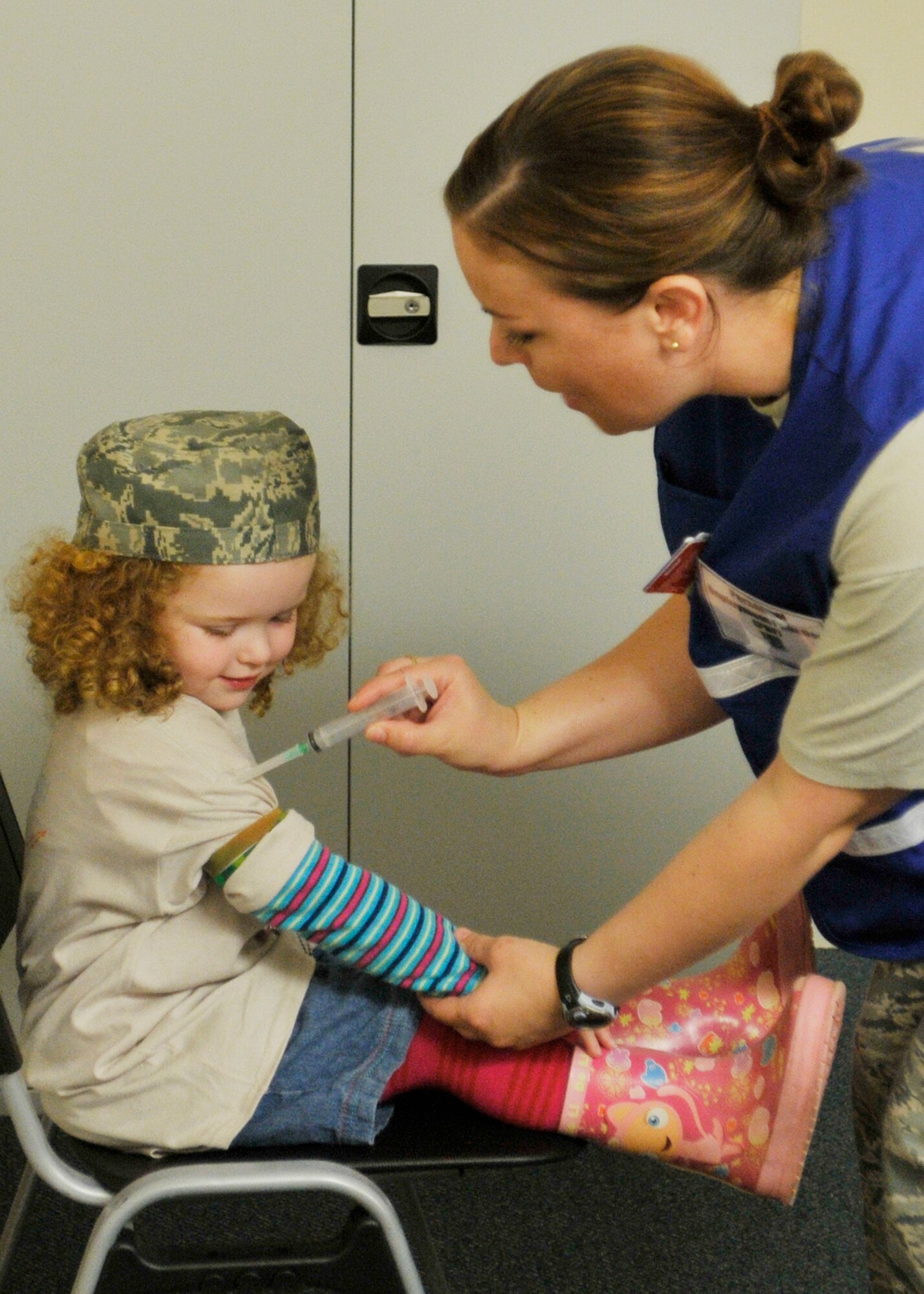 ROYAL AIR FORCE LAKENHEATH, England - Tech. Sgt. Meredith Bricker, 48th Aerospace Medical Squadron NCO in charge of deployment medicine, gives 3-year-old Jessica Lin Merrick a pretend shot during the processing line at the Installation Deployment Readiness Center for a simulated deployment line, Aug. 25, 2011. The mock deployment line is designed to provide children with a better understanding of what their parents experience as they prepare for deployment. (U.S. Air Force photo/Senior Airman Tiffany M. Deuel)