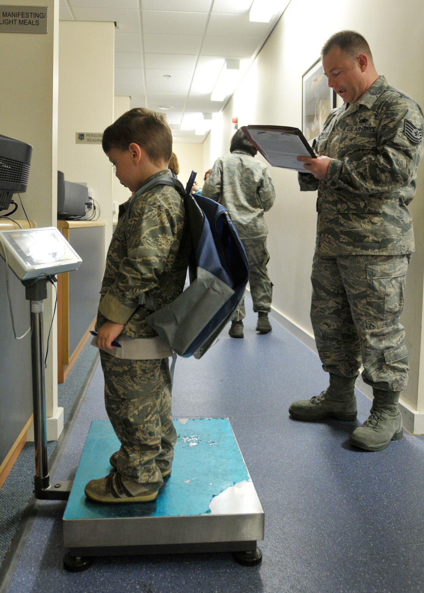 ROYAL AIR FORCE LAKENHEATH, England - Tech. Sgt. Jeremy Aumiller, 48th Force Support Squadron Readiness NCO (right),  annotates the weight of 3-year-old Brent Leaver on his deployment checklist as he processes through the line at the Installation Deployment Readiness Center for a simulated deployment line, Aug. 25, 2011. The mock deployment line is designed to provide children with a better understanding of what their parents experience as they prepare for deployment. (U.S. Air Force photo/Senior Airman Tiffany M. Deuel)