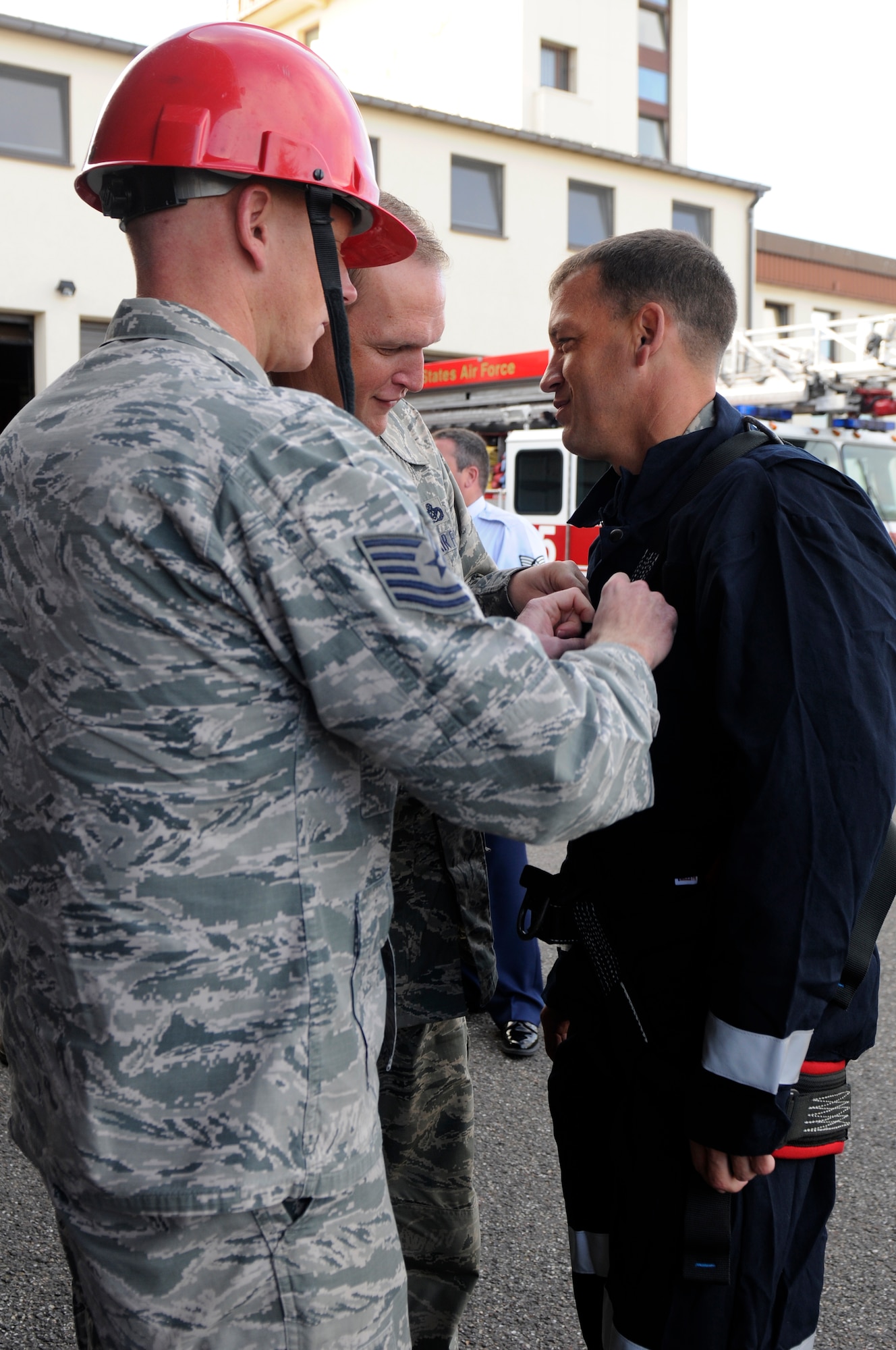 SPANGDAHLEM AIR BASE, Germany -- Tech. Sgt. Zachary McKinney, 52nd Civil Engineer Squadron Fire Department captain, left, and Master Sgt. Jon Silvis, 52nd CES Fire Department assistant chief, middle, help Senior Master Sgt. Paul Schmidt, 52nd CES first sergeant, gear up to rappel from the control tower here Aug. 29. Fire fighters with 52nd CES train to rappel so they can be proficient in high-angle rescue techniques. (U.S. Air Force photo/ Airman 1st Class Brittney Frees)