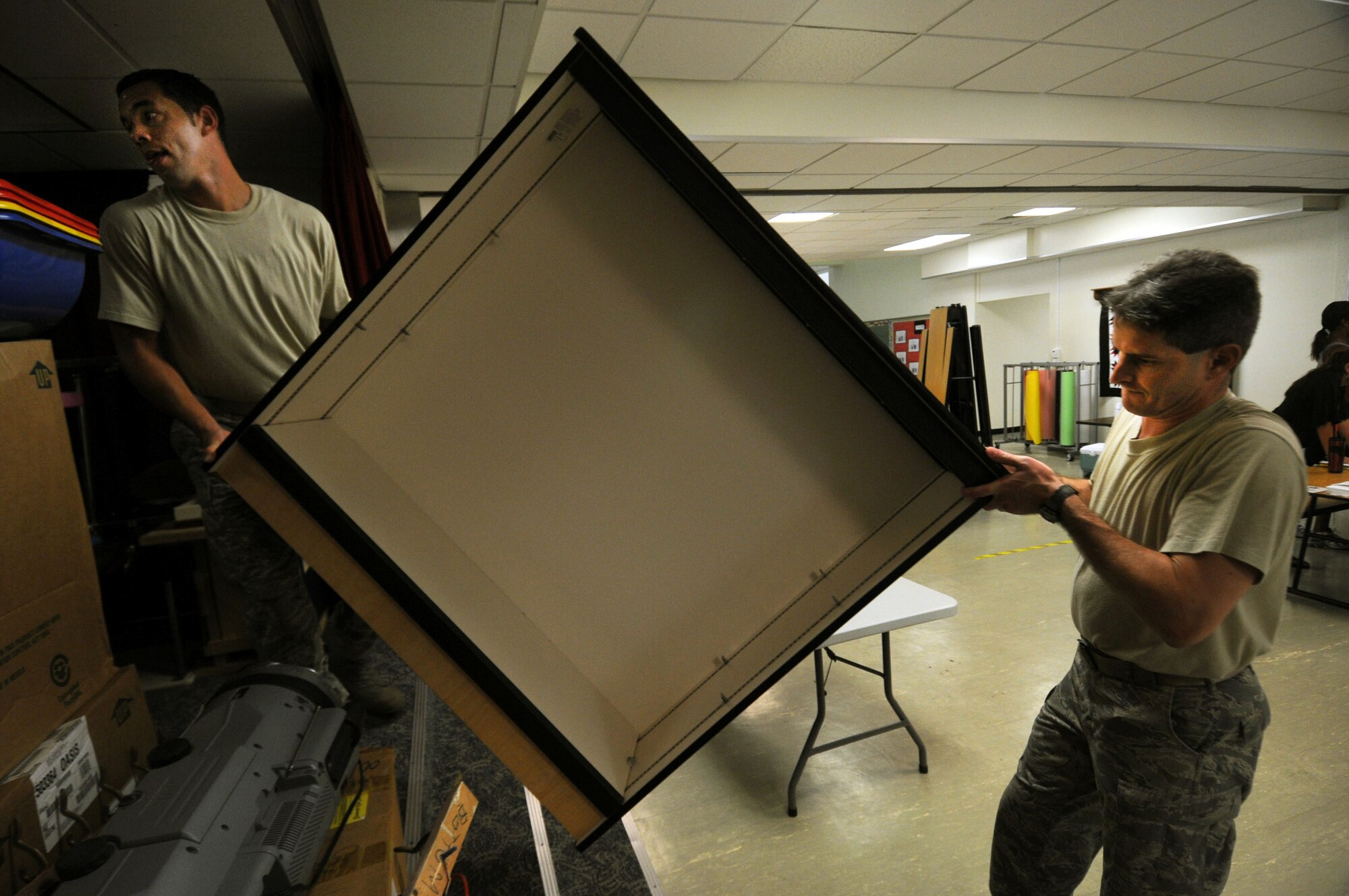 Staff Sgt. Brandon Wall, from the 390th Intelligence Squadron, carries a book shelf with the help of Master Sgt. Mark Angelico, from the 18th Contracting Squadron, to a storage area at Bob Hope Elementary School at Kadena Air Base, Japan, Aug. 26, 2011. More than 100 Airmen from all over Kadena volunteered to help move furniture and supplies at the school after Typhoon Mufia damaged some of the storage areas and classrooms. (U.S. Air Force photo by/Senior Airman Sara Csurilla)