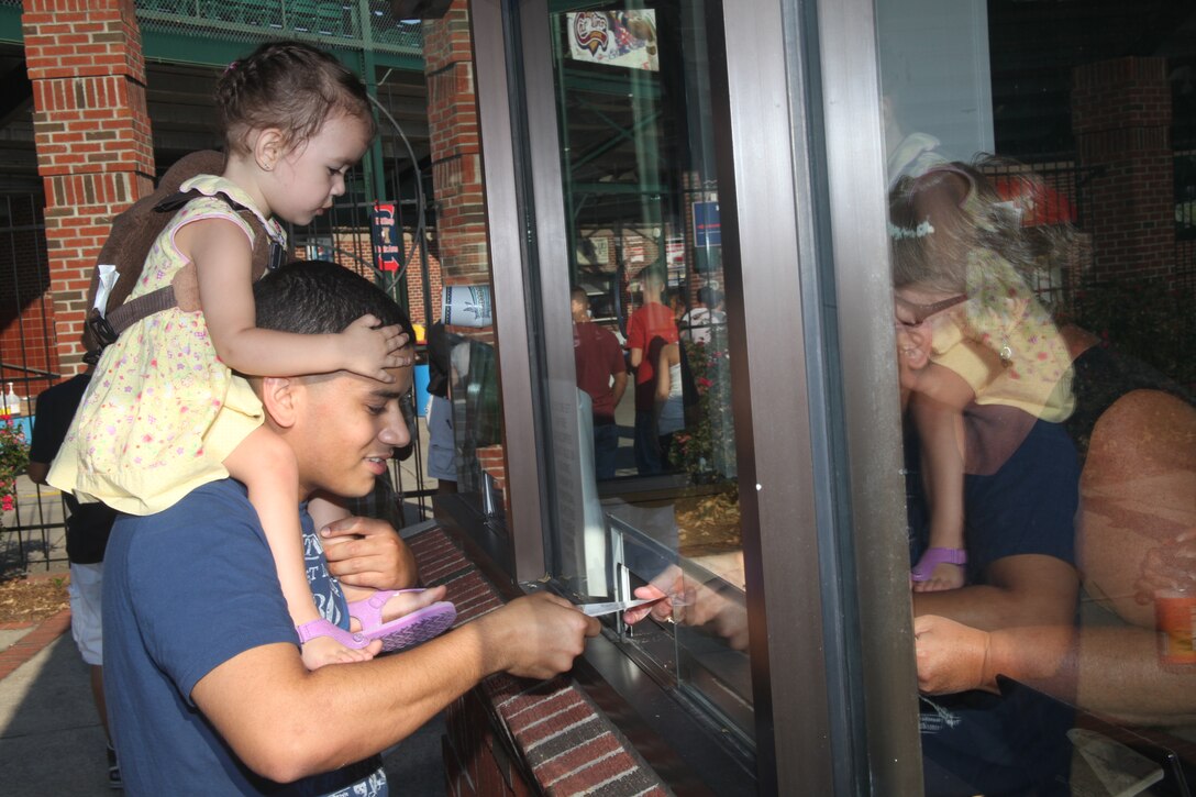 Sgt. Joshua Nieves, an airframe mechanic for Marine Tactical Electronic Warfare Squadron 3, and Jasmine N. Nieves, his daughter, collect their tickets for a Kinston Indians game, Aug. 31. All the family members were welcome to come for the party, which can help family members develop a supportive social network to use when their Marine spouses are deployed.