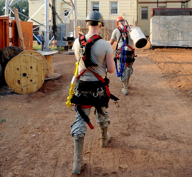 Airmen from the 85th Engineering and Installation Squadron, Keesler Air Force Base, Miss., carry their gear to a tower in front of the 2nd Civil Engineer Squadron building on Barksdale AFB, La., Aug. 31. The 85th EIS Airmen are here on temporary duty from Keesler to assist the 2nd Communications Squadron in the construction of the Command Post tower. (U.S. Air Force photo/Senior Airman Amber Ashcraft) (RELEASED)