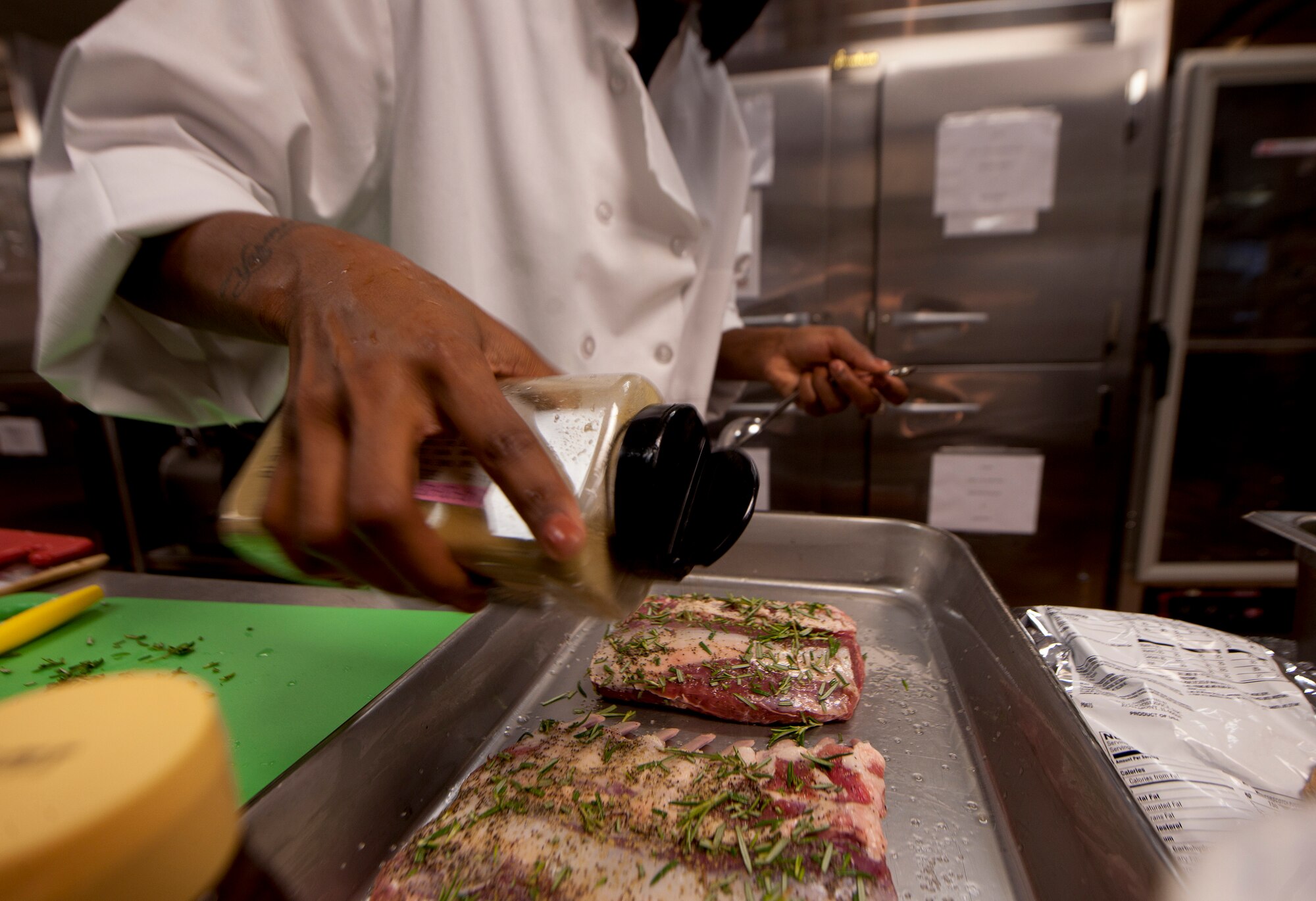 Garlic seasoning is sprinkled on to lamb chops by an Iron Chef competitor at Moody Air Force Base, Ga., Aug. 30, 2011. Lamb was the secret ingredient used by the team during their cooking process. (U.S. Air Force photo by Airman 1st Class Joshua Green/Released)
