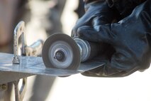 Team members participating in the 402nd EDMX exercise cut a piece of sheet metal to repair battle damage to an aircraft after a simulated attack on their base. U. S. Air Force photo by Sue Sapp