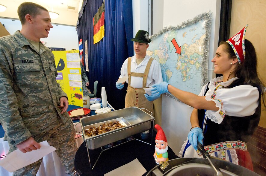 Staff Sgt. Chelsie Miller (right), a maintenance qualifications training program instructor with the 436th Maintenance Operations Squadron, hands Airman 1st Class Sam Belcher, a heating, ventilation and air conditioning apprentice with the 436th Civil Engineer Squadron, authentic German food during the multi-cultural expo Aug. 26, 2011, at The Landings Club at Dover Air Force Base, Del. The multi-cultural expo was held to celebrate Team Dover’s diversity. (U.S. Air Force photo by Airman 1st Class Samuel Taylor)