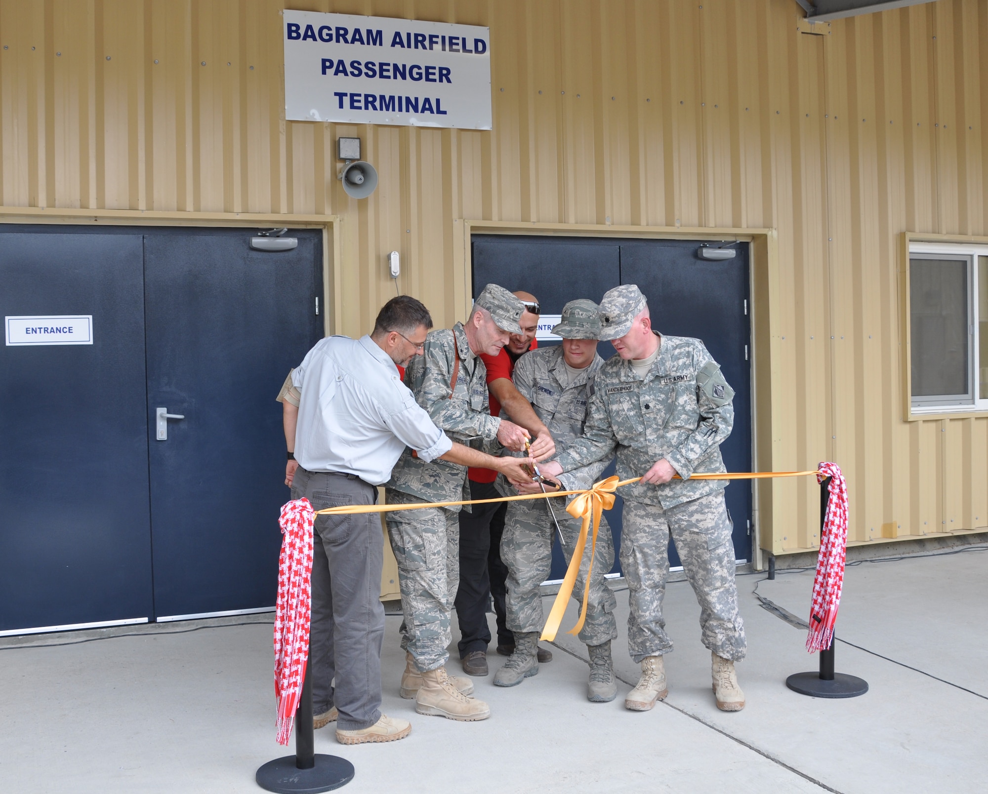 BAGRAM AIRFIELD, Afghanistan -- Brig. Gen. Darryl Roberson, 455th Air Expeditionary Wing commander, Army Lt. Col. Douglas Vanderhoof, Bagram Area Corps of Engineers officer in charge, Senior Airman Justin Shenck, 455 Expeditionary Aerial Port Squadron passenger terminal journeyman and members from a civilian construction company cut a ribbon during the opening of a new passenger terminal here Aug. 31,2011. (U.S. Air Force photo/Staff Sgt. John Wright) 