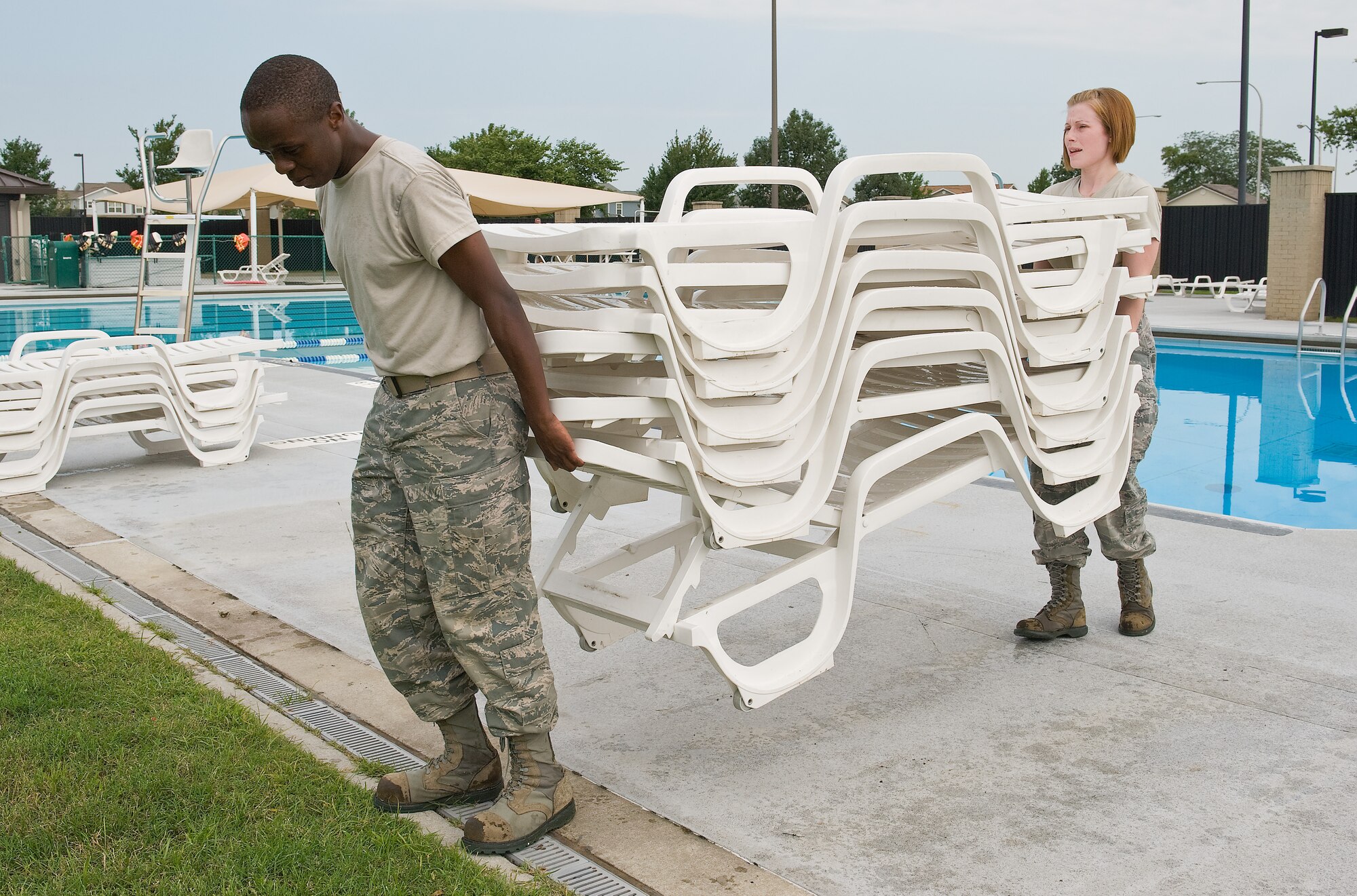 Airman 1st Class Paul Mutwiri and Senior Airman Alicia Jarrell, both assigned to the 436th Force Support Squadron, move pool chairs to a secure location Aug. 25, 2011, at the Oasis Base Pool at Dover Air Force Base, Del. (U.S. Air Force photo by Roland Balik)