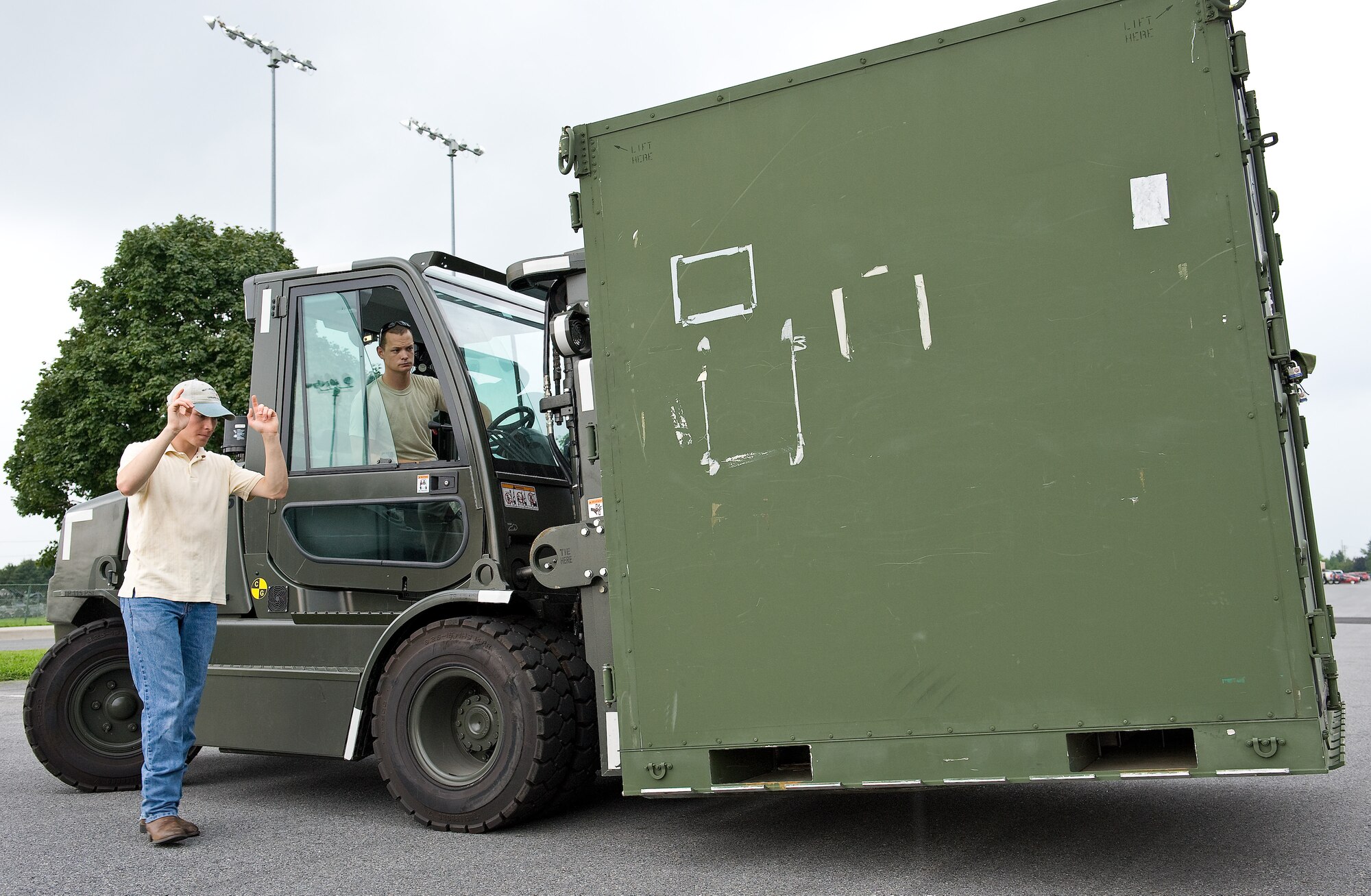 Staff Sgt. Benjamin Putnam, 436th Operations Support Squadron, marshalls Senior Airman Mitchell Scott, 436th Civil Engineer Squadron, as he moves a equipment container into a storage facility Aug. 25, 2011, on Dover Air Force Base, Del. All items normally stored outside were placed in buildings and aircraft hangars in preparation for the arrival of Hurricane Irene. (U.S. Air Force photo by Roland Balik)