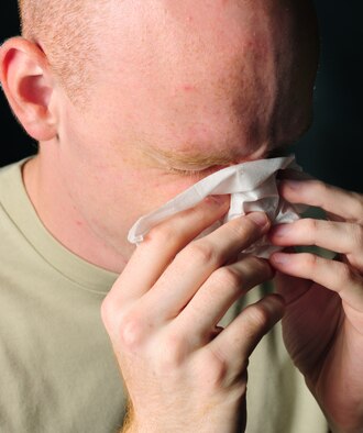 Man blowing nose into Kleenex 
