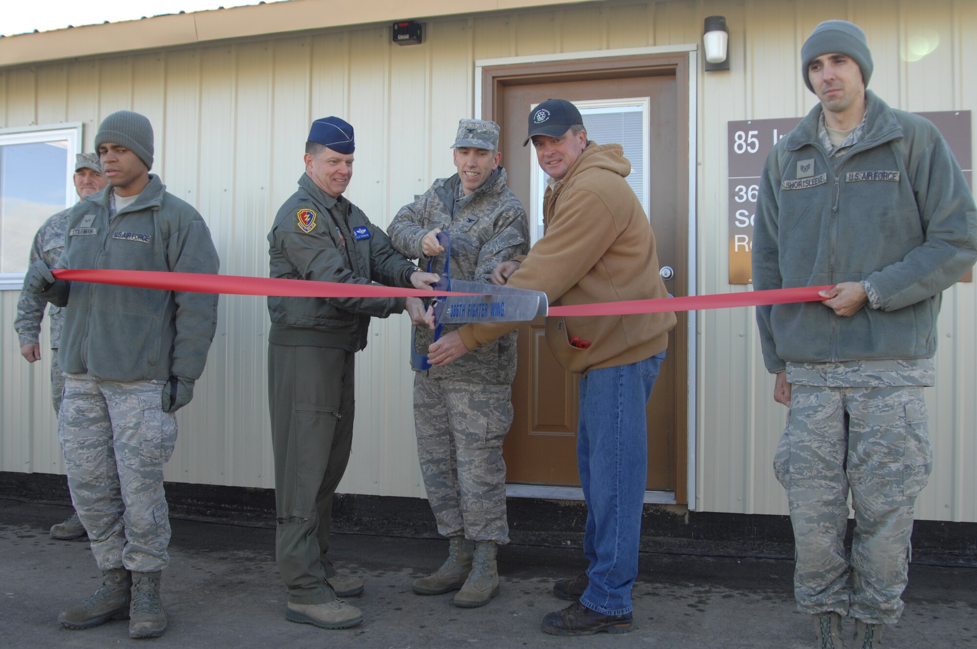 From left, Col. Kyle Robinson, 366th Operations Group commander, Col. Scott Moser, 366th Mission Support Group commander, and Ed Jackson, recycle program manager, cut the ceremonial ribbon Nov. 30, 2011, during the opening of the new recycle center office building at Mountain Home Air Force Base, Idaho.  The construction took more than three months to complete with senior civilians and military leaders mentoring younger Airmen throughout the project. (U.S. Air Force photo by Senior Airman Benjamin Sutton)