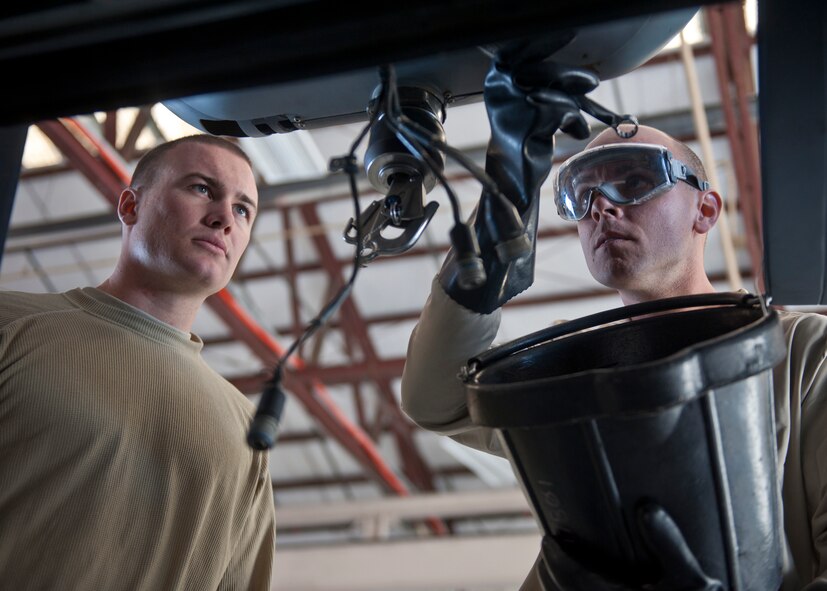 U.S. Air Force Airman 1st Class Joshua Jaynes, 723rd Aircraft Maintenance Squadron, right, drains hydraulic fluid from an HH-60G Pave Hawk while Airman 1st Class Matthew Schroth, 23rd Component Maintenance Squadron, keeps a watchful eye at Moody Air Force Base, Ga., Nov. 30, 2011. The HH-60 recently returned from depot maintenance, where more in-depth and detailed inspections take place for the aircraft every 1,200 flying hours before being sent back to Moody to continue to receive general maintenance. (U.S. Air Force photo by Senior Airman Eileen Meier/Released)
