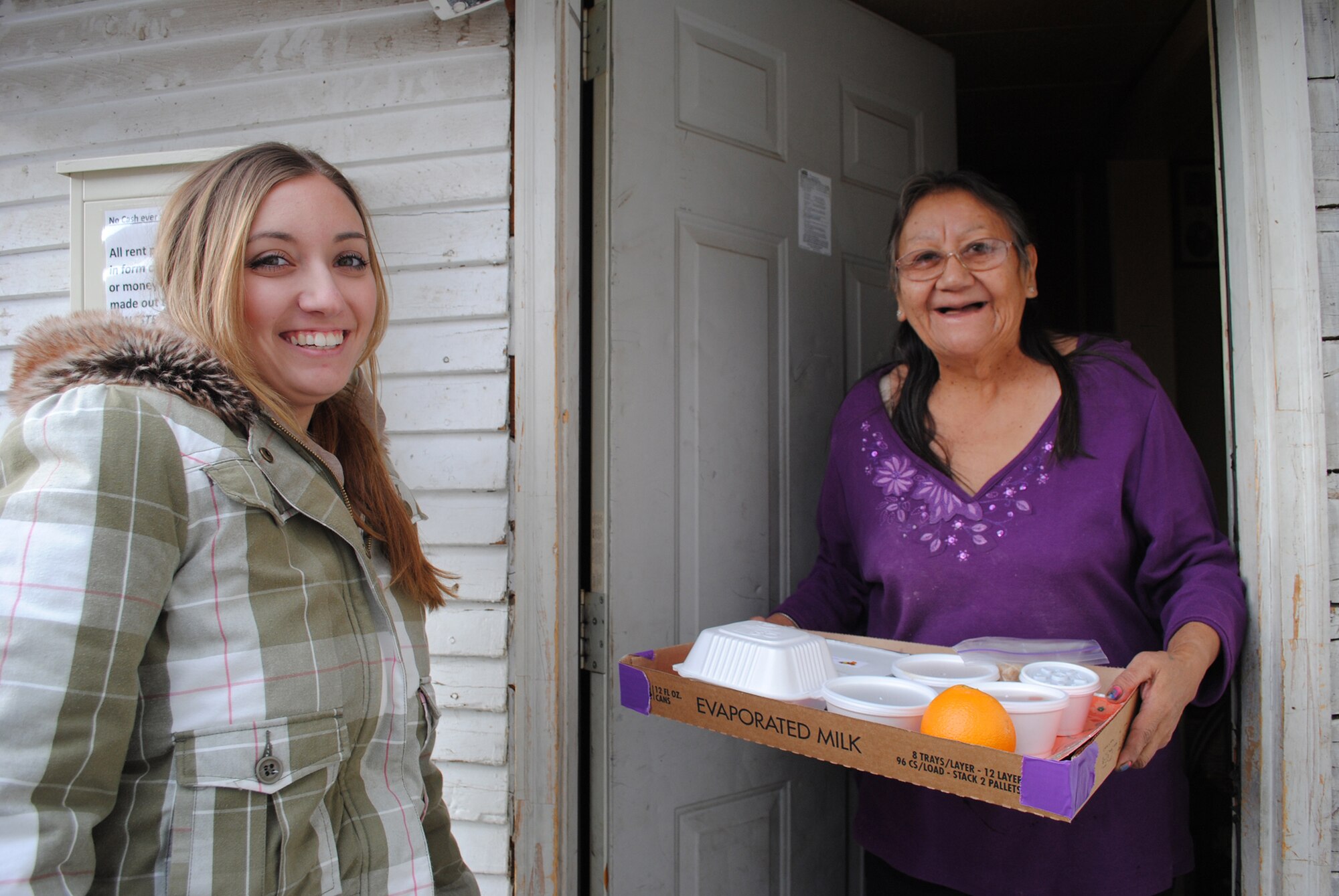 Clara Donney, (right), a Meals on Wheels recipient of a Thanksgiving dinner sponsored by the Great Falls Community Food Bank, is all smiles as Airman 1st Class Courtney Taylor, customer service technician with the 341st Comptroller Squadron, delivers her meal. (U.S. Air Force photo/Airman 1st Class Katrina Heikkinen)