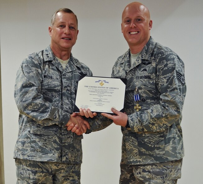 U.S. Air Force Maj. Gen. Lawrence Wells, 9th Air Force commander, presents Staff Sgt. Anthony Deroest, 38th Rescue Squadron pararescueman, with a Distinguished Flying Cross Medal at Moody Air Force Base, Ga., Nov. 30, 2011. The Distinguished Flying Cross is awarded to members who distinguish themselves in support of operations by extraordinary achievement while participating in an aerial flight. (U.S. Air Force photo by Airman 1st Class Olivia Dominique/Released) 