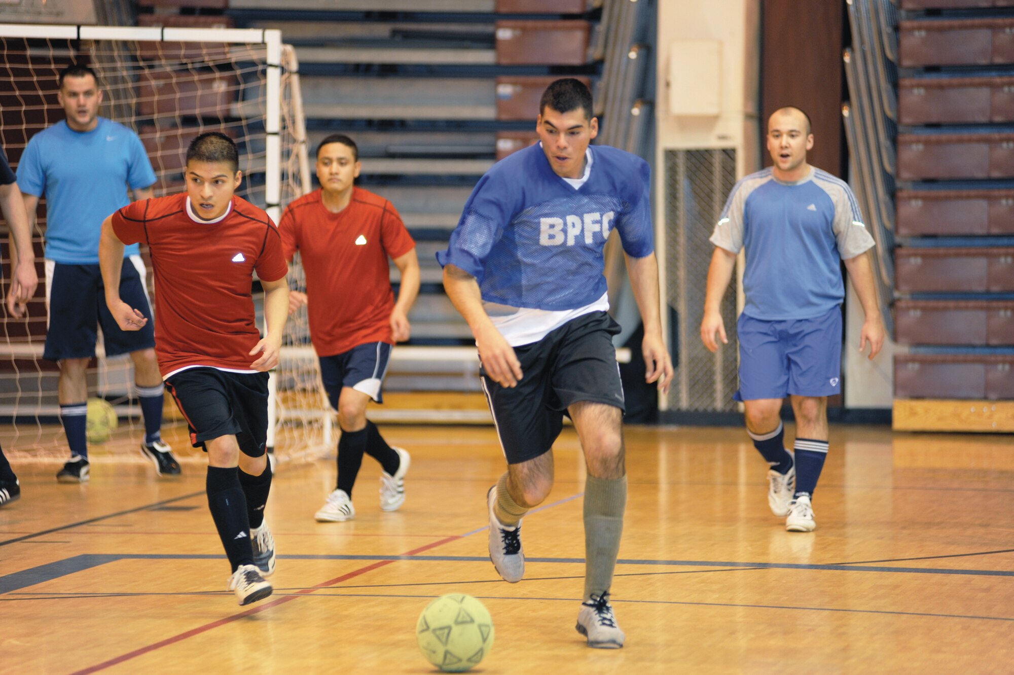 Miguel Murillo, center blue, takes the ball away from his team's goal during the playoff finals between the Army 56th Engineer Company and the Army 381st Intelligence Squadron in the Buckner Physical Fitness Center Nov. 26, 2011. The reds, representing the 56th Engineer Company, beat the blues, representing the 381st Intelligence Squadron, 7 to 4, earning 3rd place in the finals. The Army 95th Chemical Company earned 1st place and the Army F Company 725 earned 2nd place. (U.S. Air Force photo/Staff Sgt. Robert Barnett)