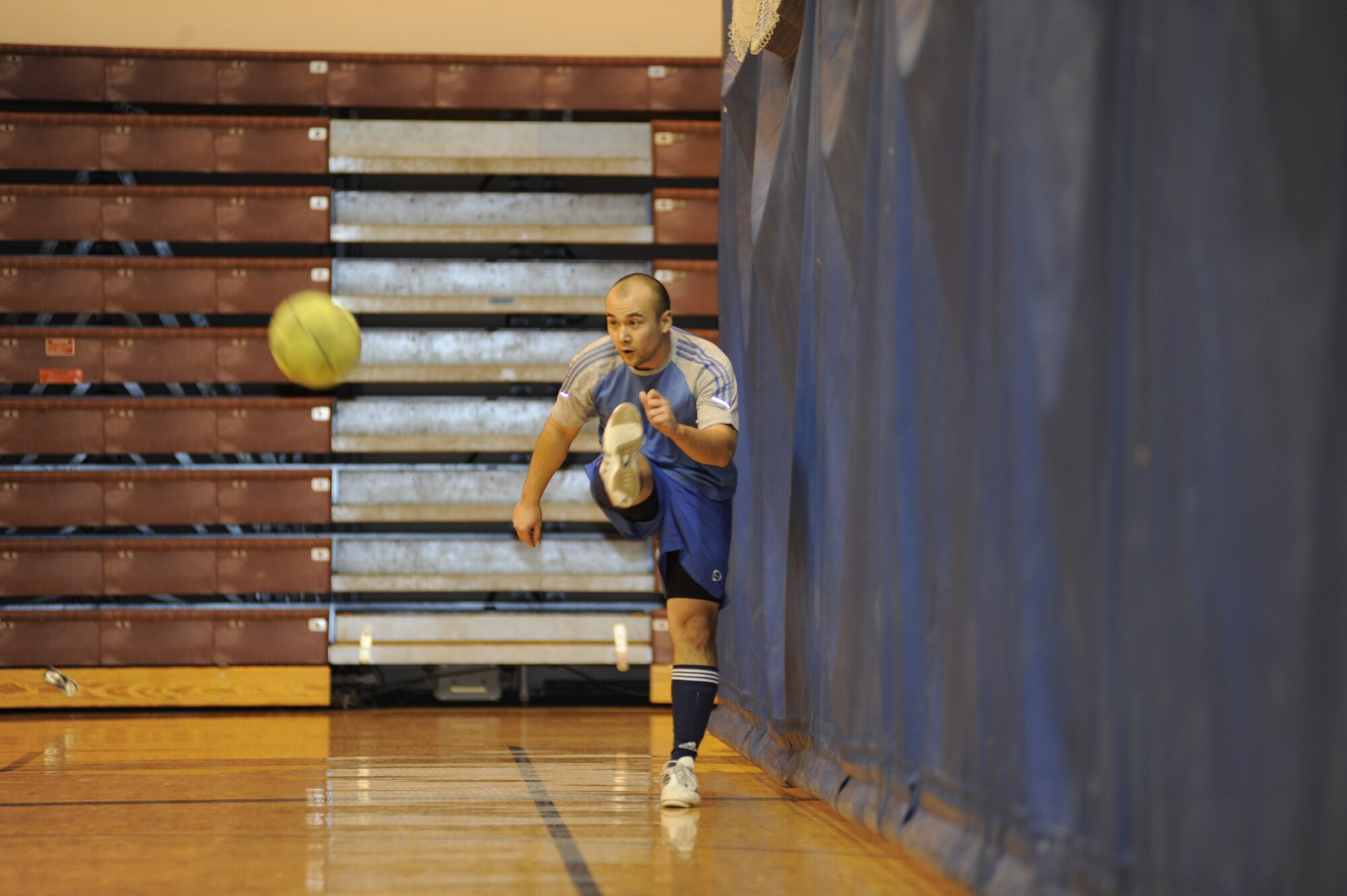 Ryan Matthews kicks the ball back into the game during the playoff finals between the Army 56th Engineer Company and the Army 381st Intelligence Squadron in the Buckner Physical Fitness Center Nov. 26, 2011. The reds, representing the 56th Engineer Company, beat the blues, representing the 381st Intelligence Squadron, 7 to 4, earning 3rd place in the finals. The Army 95th Chemical Company earned 1st place and the Army F Company 725 earned 2nd place. (U.S. Air Force photo/Staff Sgt. Robert Barnett)