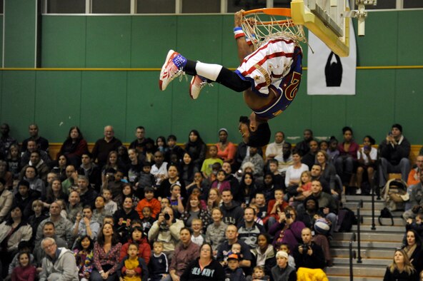 Ant Atkinson, Harlem Globetrotter member, hangs upside down from a basketball hoop at the Edgren High School gymnasium Misawa Air Base, Japan, Nov. 30, 2011, during their 11th annual holiday tour. The Harlem Globetrotters are an exhibition basketball team that combine athleticism, theater and comedy into their routines. (U.S. Air Force photo/Tech. Sgt. Marie Brown/Released) 
