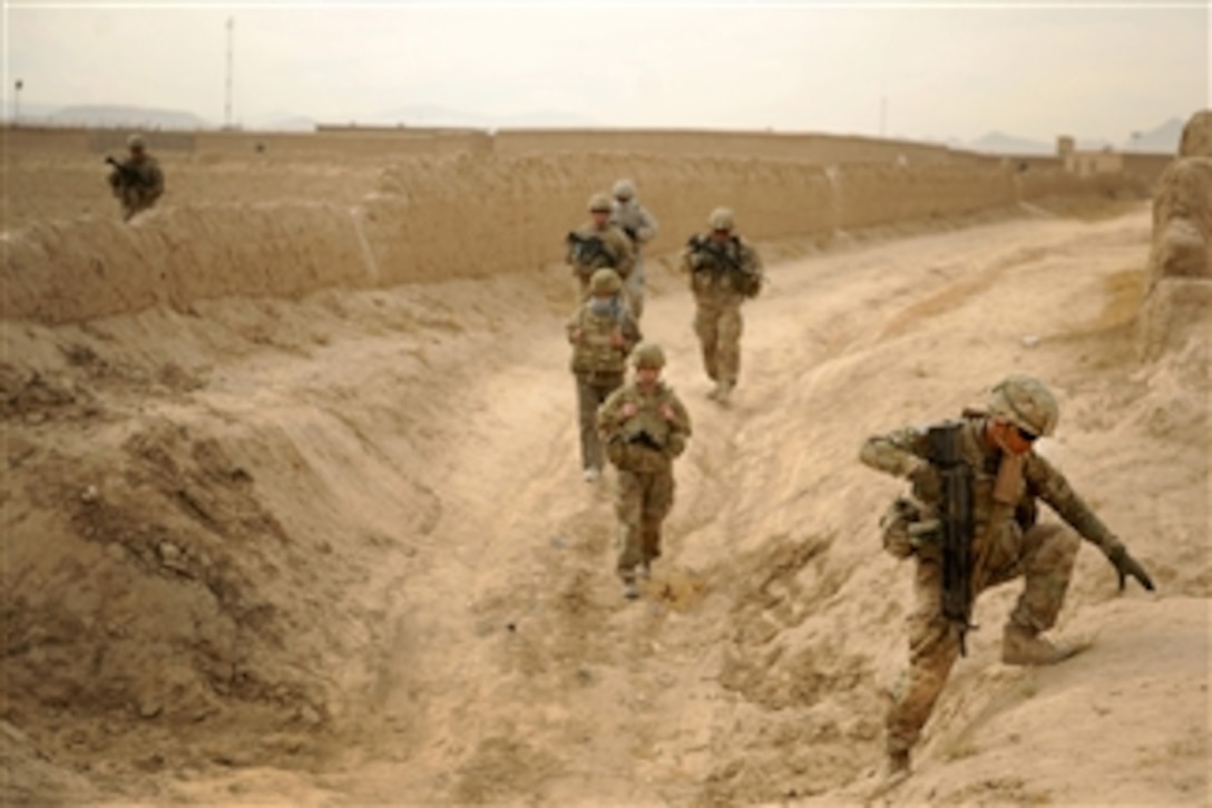 U.S. Army Spc. Edwarde Loeup (right), an automatic rifleman with Provincial Reconstruction Team Zabul, moves to high ground during a dismounted patrol on the way to a key leader engagement at a hospital in Shah Joy, Afghanistan, on Nov. 21, 2011.  