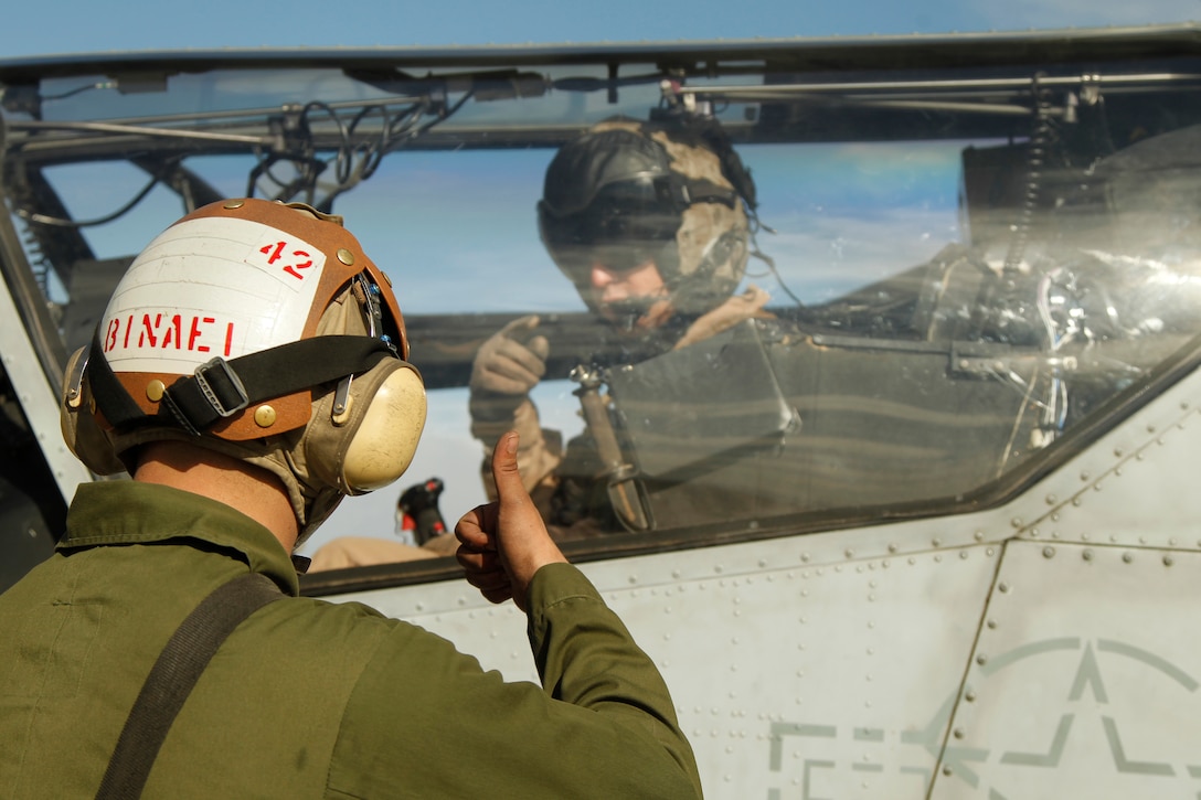 Lance Cpl. Kyle Binaei gives the UH-1N Huey pilot a thumbs up, signaling to him that the helicopter’s engine is good for take off during a daily turnaround inspection Dec. 2, 2011.
