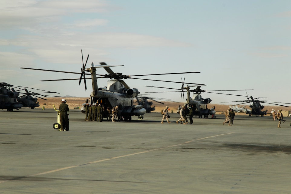 Marines hop off of a CH-53E Super Stallion  as aviation maintenance Marines prepare to do a daily turnaround inspection Dec. 2, 2011, at Camp Wilson. The inspection is conducted after every aircraft has landed.