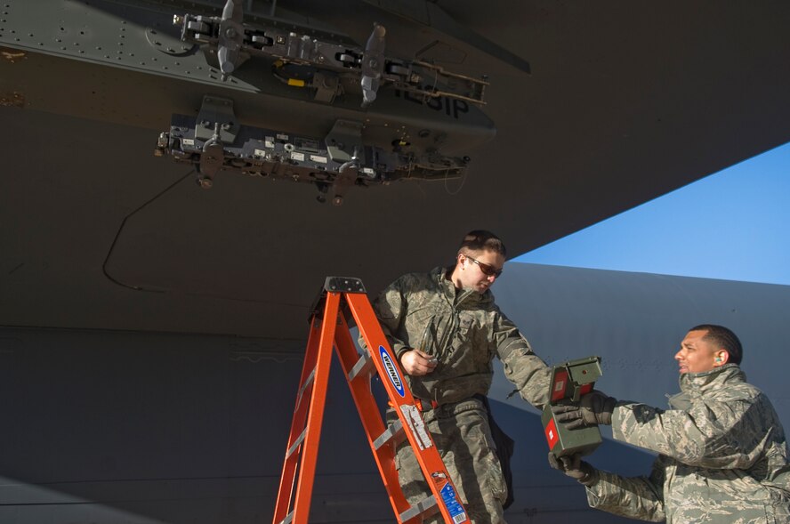 Staff Sgt. Bryan Tune, 2nd Maintenance Operations Squadron, reaches for an impulse cartridge from Tech. Sgt. Marlon George, 2 MOS, to be attached to a heavy stores adaptor beam on a B-52H Stratofortress on Barksdale Air Force Base, La., Nov. 30. Impulse cartridges are used to help release bombs when being dropped from the aircraft. (U.S. Air Force photo/Senior Airman Kristin High)(RELEASED)