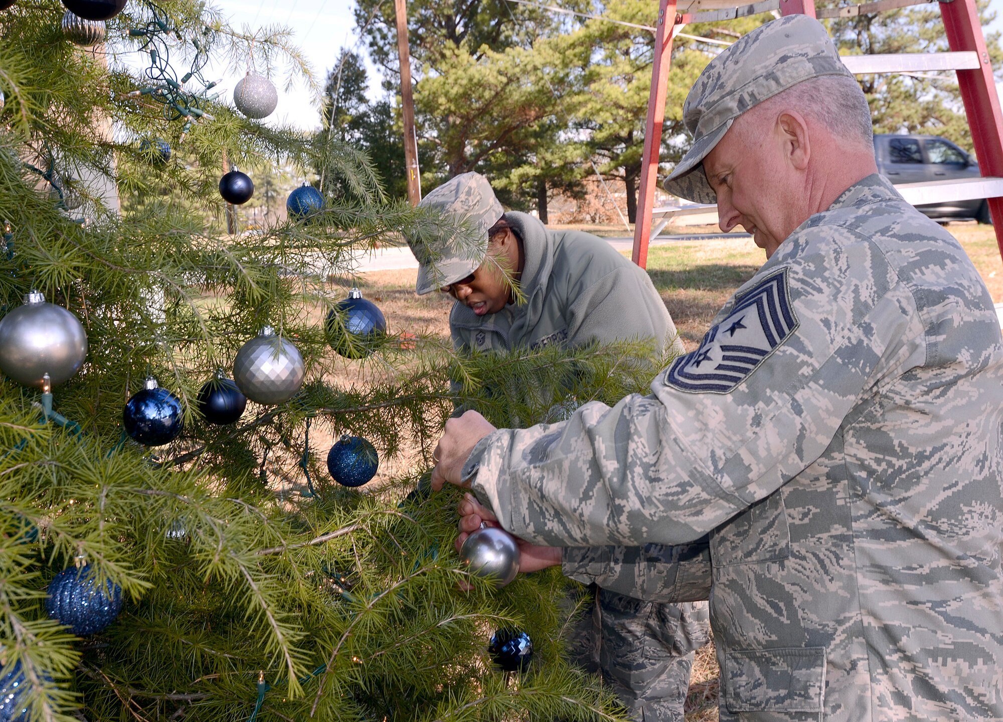 Chief Master Sgt. Wendell Peacock, 94th Airlift Wing command chief, places decorations on the wing Christmas tree as Master Sgt. Patrina Sheffield, 94th Maintenance Squadron 1st Sgt. Does the same in the background, Dec. 2.   (U.S. Air Force photo/ Brad Fallin)