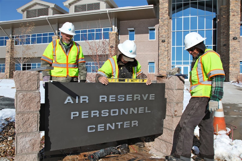 A construction crew works at installing the building sign in front of the headquarters building at the Air Reserve Personnel Center Dec. 2, 2011, on Buckley Air Force Base, Colo. The sign, which has been refurbished, was originally used at ARPC's previous location on Lowry AFB, Colo. (U.S. Air Force photo/Quinn Jacobson)