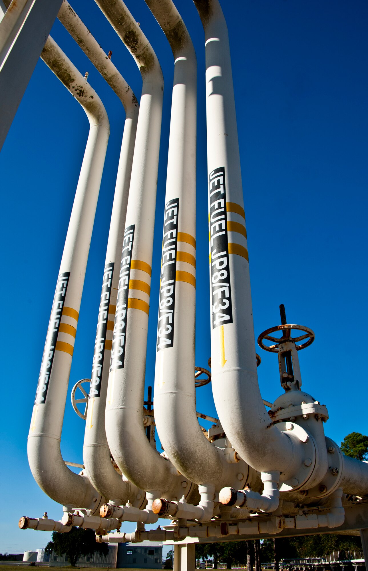 A series of five pipes deliver Air Force JP-8 from a barge to a bulk storage tank on Eglin Air Force Base, Fla.  After moving the fuel from barge to bulk storage, the fuel must be isolated for eight hours.  Eventually, fuel moves from bulk storage to an operational storage tank before being loaded into a tanker truck and delivered to the aircraft.  (U.S. Air Force photo/Samuel King Jr.)