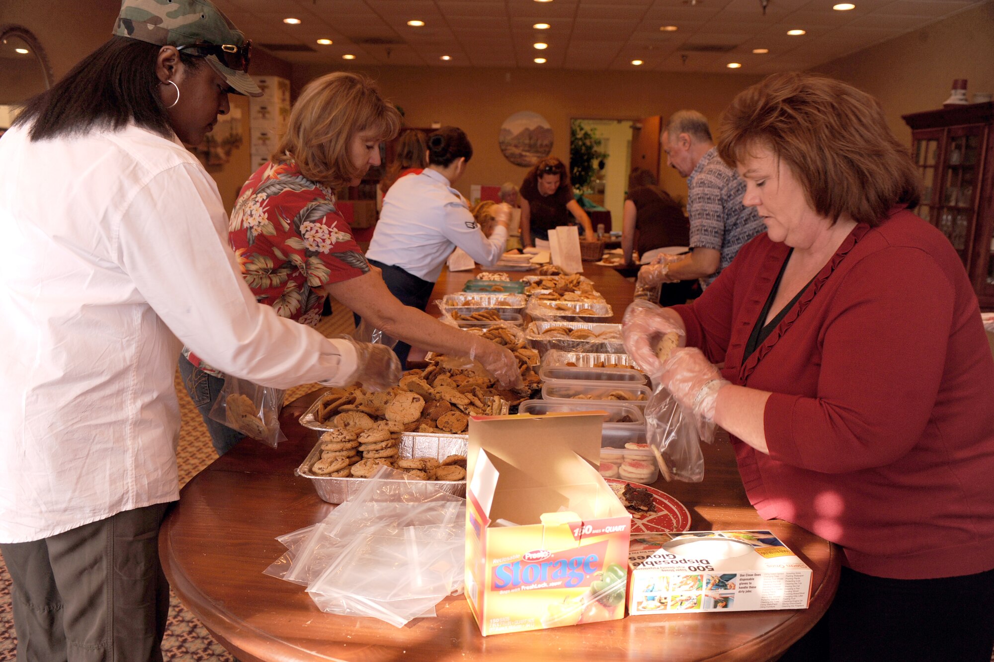 Volunteers form an assembly line on each side of the table for the annual  cookie crunch on Davis-Monthan Air Force Base, Ariz., Nov. 28, 2011. The goal of the D-M Officer Spouses Club is to deliver more than 2,000 bags of cookies to single Airman on and off base. (U.S. Air Force photo by Airman 1st Class Christine Griffiths/Released) 