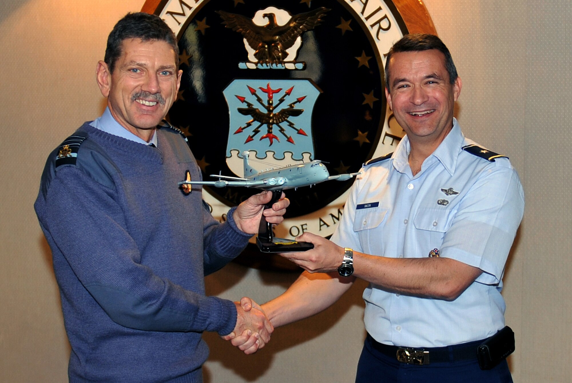 Air Chief Marshal Sir Simon Bryant, U.K. Royal Air Force commander-in-chief air command, presents a RAF Nimrod R1 model aircraft to Brig. Gen. Donald Bacon, 55th Wing commander, inside the Patriot Club at Offutt Air Force Base, Neb., on Nov. 28. Bryant was at Offutt to get a closer look at how the 55th WG is providing RC-135V/W Rivet Joint initial qualification training to his fellow Airmen. The U.K. is purchasing three RJs over the next seven years to replace the retiring Nimrod. (Air Force photo by Jeff Gates)