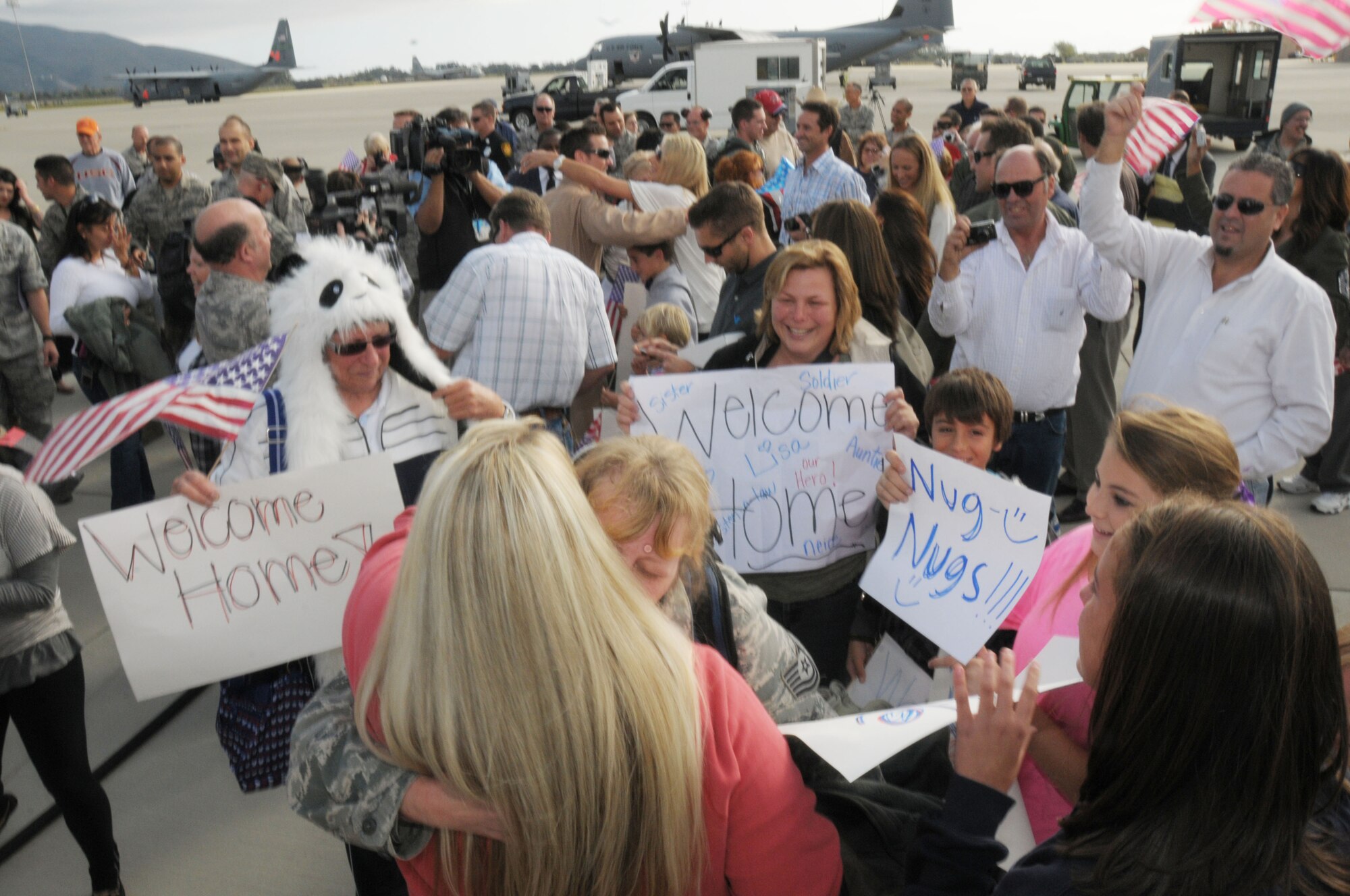 Family members of airmen returning from an overseas deployment hold up 'Welcome Home' signs and embrace their loved ones from the 146th Airlift Wing at Channel Islands Air National Guard Station on November 23, 2011. Members returned home from a 90 day AEF rotation in Afghanistan, just in time for Thanksgiving. 