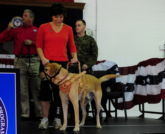 Retired Army Capt. Leslie Smith takes her place on stage with her service dog, Issac, during a ceremony at the Naval Consolidated Brig Charleston Dec. 1. During the ceremony, the NAVCON Brig, in partnership with Carolina Canines for Service, presented Marine Cpl. David Donchess, a wounded service member, his service dog, Ruth. Smith lost her left leg and eye-sight after contracting a blood disorder while on duty in Bosnia in 2002 and now travels extensively on behalf of organizations such as the Wounded Warrior Project, Iraq Star Foundation, Army Wounded Warrior Program, Operation Heroes and Disabled Sports USA. CCFS is a non-profit health and human services organization that trains service dogs for people with disabilities. Through this program, military prisoners are taught to train service dogs for veterans with disabilities. Since the program's inception, 14 wounded service members have received service dogs. (U.S. Air Force photo/ Staff Sgt. Nicole Mickle)  