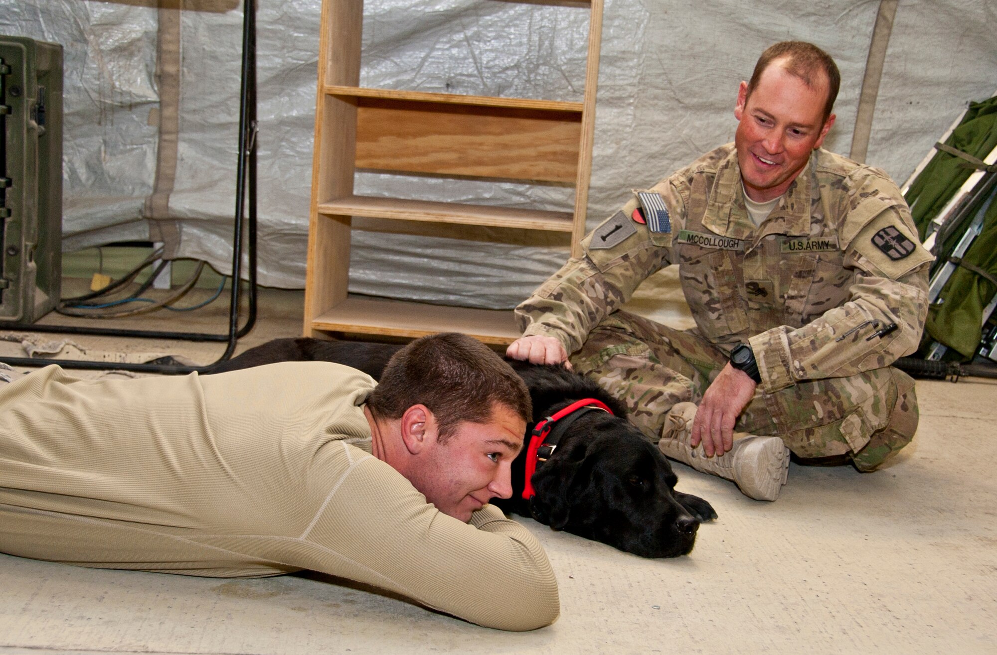 KANDAHAR AIRFIELD, Afghanistan -- Senior Airman Travis Williams, a radar maintenance technician with the 73rd Expeditionary Air Control Squadron, lays next to Sgt. 1st Class Zeke, a combat stress dog from Kandahar Airfield's Role 2, Dec. 1, 2011. As a combat stress dog, Zeke and his handler, Army Sgt. Paul McCollough, visit patients at Role 3 and requesting units around KAF to increase morale and welfare. (U.S. Air Force photo by Staff Sgt. David Carbajal)