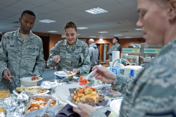 Senior Airman Thomas Jean, 39th Communications Squadron postal clerk, left, and Senior Airman Brianna Bergstrand, center, 39th Air Base Wing knowledge operator, get food from Master Sgt. Jamie Eichhorn, 39th Security Forces Squadron logistics superintendent, during a free Airman's dinner at The Connection Dec. 1, 2011, at Incirlik Air Base, Turkey.  The Connection, a building and program run by the 39th Air Base Wing Chapel, provides unaccompanied Airmen sanctuary from the hectic bustle outside the building’s walls. (U.S. Air Force photo by Senior Airman Anthony Sanchelli/Released)
