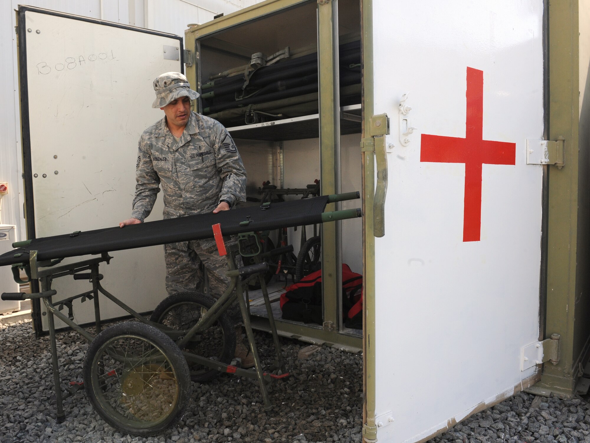 Master Sgt. Leonel Gonzalez sets up a litter in front of one of two medical containers at the 380th Air Expeditionary Wing Nov. 25, 2011. Each container, known as a CONEX in military jargon, is loaded with 20 litters, two litter carriers with wheels and medical kits with supplies similar to what troops will find in their improvised first aid kits. Deployed medical personnel have launched a new program that will help ensure quick access to medical supplies in the event of an emergency or mass casualty event at the 380th Air Expeditionary Wing. Gonzalez is the NCO in charge of clinical operations for the 380th Expeditionary Medical Group. He is deployed from the 779th Medical Group at Joint Base Andrews, Md., and is from Fredericksburg, Va.  (U.S. Air Force photo/Master Sgt. Chance Babin)