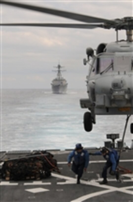 Seaman Lucio Robles (left) and Seaman Daniel Nogal clear the flight deck of the guided-missile destroyer USS Mitscher (DDG 57) after attaching a cargo net to an MH-60R Sea Hawk helicopter from Helicopter Maritime Strike Squadron 70 during a vertical replenishment at sea in the Atlantic Ocean on Nov. 29, 2011.  In the background is the guided-missile destroyer USS Truxtun (DDG 103).  The Mitscher and the Truxtun are deployed to the U.S. 6th Fleet area of responsibility conducting maritime security operations and theater security cooperation efforts.  