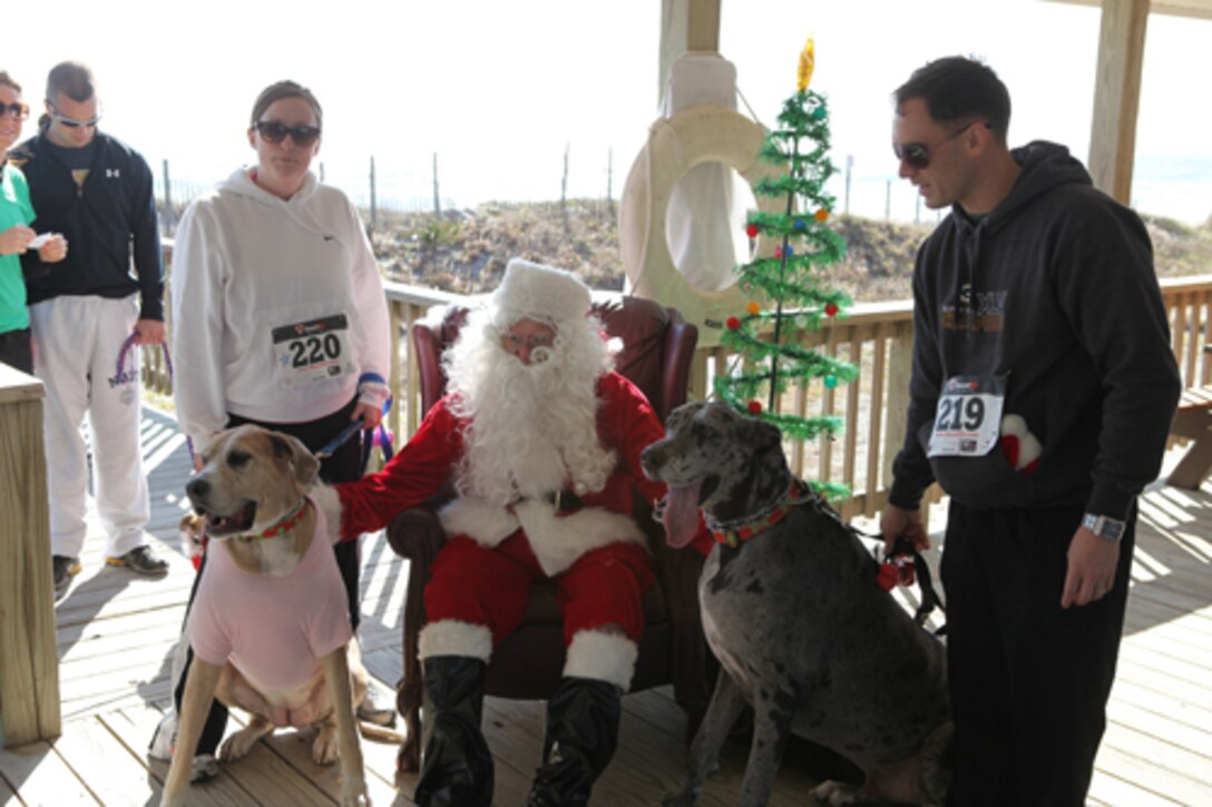 Two of the largest furry companions at the Sandy Paws Fun Run, Porsche (left), and Bentley, take a moment to pose for a photo with a canine-friendly Santa Claus and their owners, following the one-mile run, walk or jog event at Onslow Beach aboard Marine Corps Base Camp Lejeune, Dec. 3. ::r::::n::::r::::n::