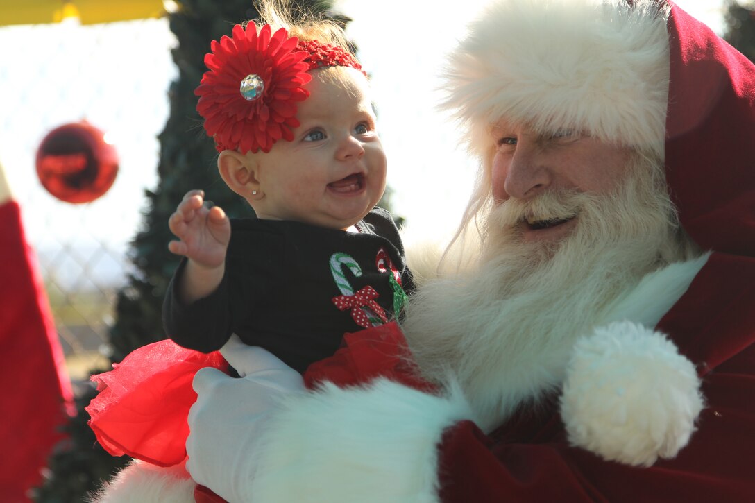 Gabriella Scitzs, 8-month-old daughter of Anjelu and Richard Scitzs, laughs as Santa plays peek-a-boo with her before their picture is taken during the installation’s annual Winter Festival at Felix Field Dec. 3, 2011.