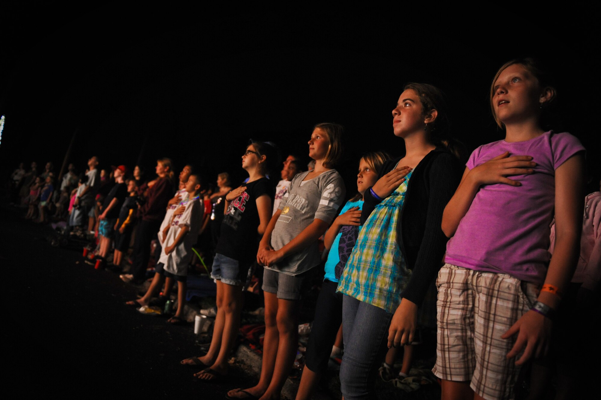 Young girls place their hand over their heart as Tops in Blue sings the National Anthem to open their show at Freedom Tower on Joint Base Pearl Harbor-Hickam, Hawaii, Dec. 2. (U.S. Air Force Photo/Senior Airman Lauren Main) 