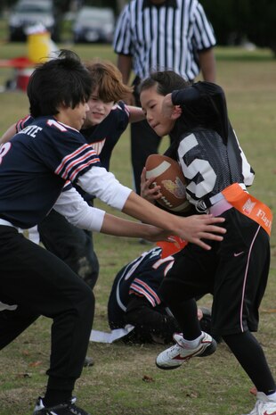 China Kumaki, Suzuhara Fighting Roses wide receiver, tries to avoid having her flag pulled of by Caeleb V. Ricafrente, Bears linebacker and wide receiver, in a Marine Corps Community Services Youth Sports double-elimination flag football tournament in the 10- 12 year old division at the Matthew C. Perry School soccer field here Sunday. The Roses routed the Bears in considerable fashion, beating the Bears 34-6.