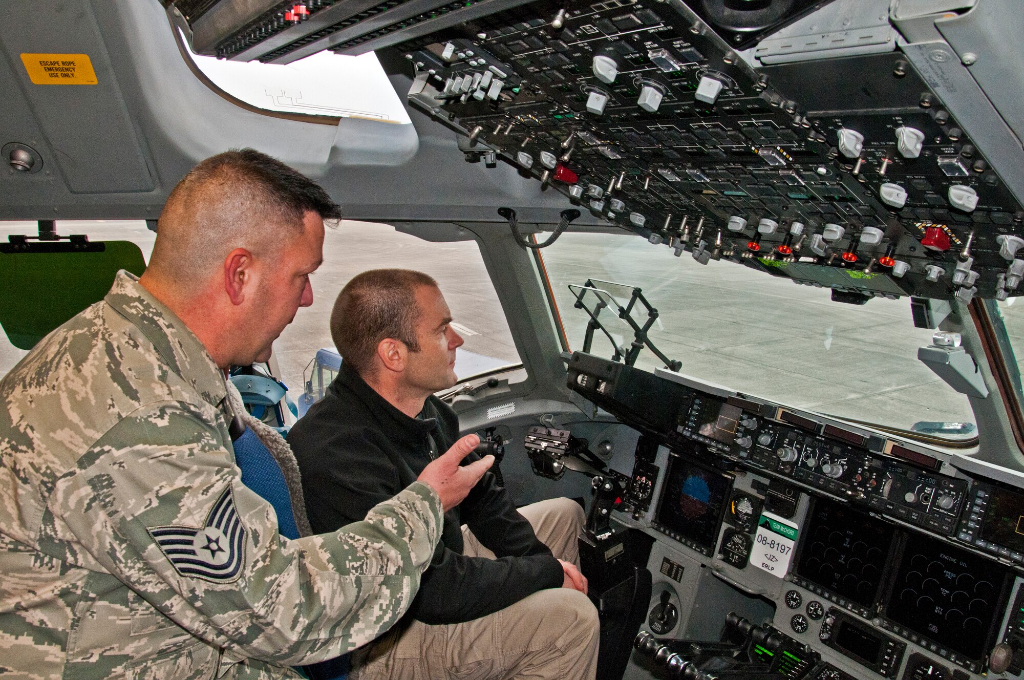 Tech. Sgt. David Gallegos, 446th Aircraft Maintenace Squadron crew chief, teaches Iain Harrison, the first season winner of the History Channel's "Top Shot," about the heads-up display aboard a C-17 Globemaster III Dec. 3, 2011 at Joint Base Lewis-McChord, Wash. Harrison first set foot on McChord Field as a member of the British Army twenty years earlier and returned to take his Oath of Allegiance to become an American citizen. (U.S. Air Force photo by Tech. Sgt. Tanya King/Released)