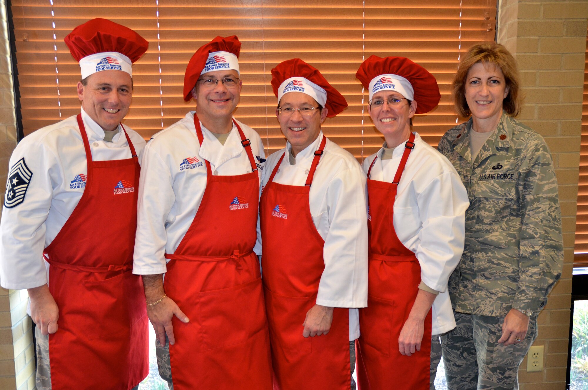 Senior leadership from the 512th Airlift Wing donned their aprons to serve the holiday meal to reservists Dec. 4, 2011 at the Patterson Dining Facility, Dover Air Force Base, Del. Maj. Beth Bruker Walos (right), the commander of the 512th Memorial Affairs Squadron which oversees dining facility operations, was present at the event. Left to right: Chief Master Sgt. William T. Wild III, 512th AW command chief, Col. Randal L. Bright, 512th AW  commander, Col. Clifford Zdanowicz, 512th Aerospace Medicine Squadron, and Col. Gretchen Wiltse, 512th Mission Support Group commander. (U.S. Air Force photo by Staff Sgt. Danella Shea/Released)