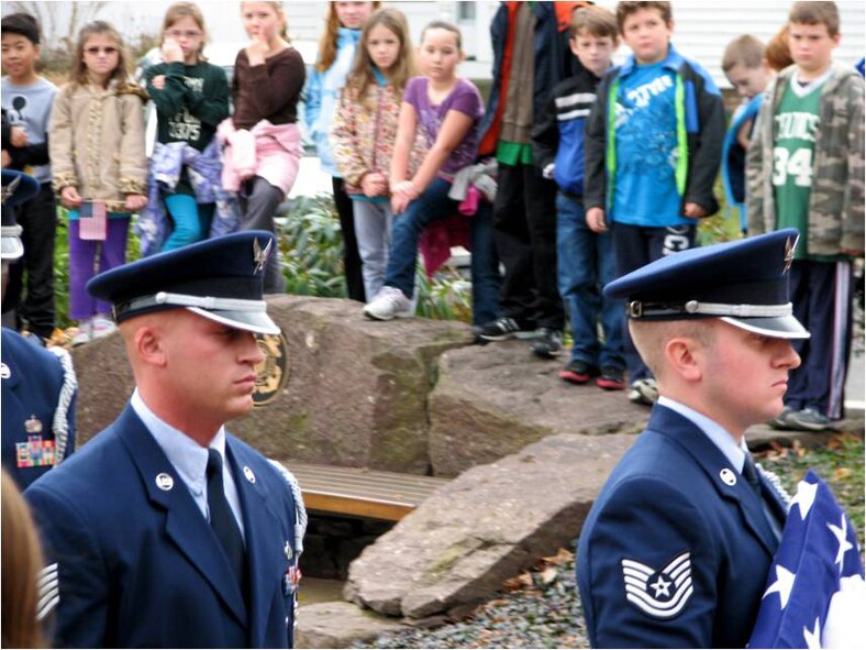 Technical Sergeants Matt Swindlehurst (right) and Dana Granteed, both of the 439th Airlift Wing honor guard, carry the U.S. flag after after lowering it from half staff and folding it as part of a Veteran's Day ceremony in Sunderland, Mass.