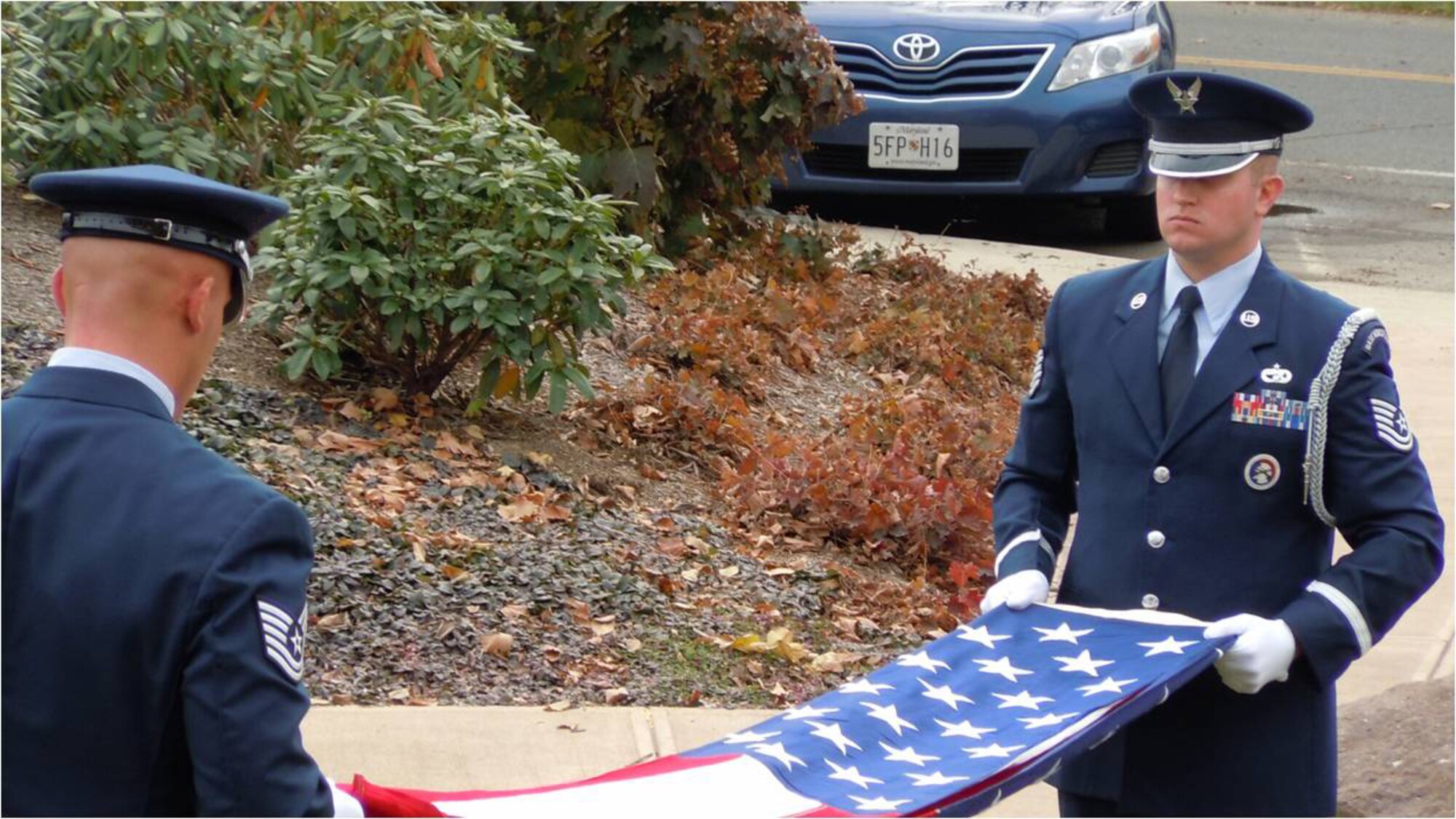 Technical Sergeants Matt Swindlehurst (right) and Dana Granteed, both of the 439th Airlift Wing honor guard, fold the U.S. flag after lowering it from half staff during a Veteran's Day ceremony in Sunderland, Mass.