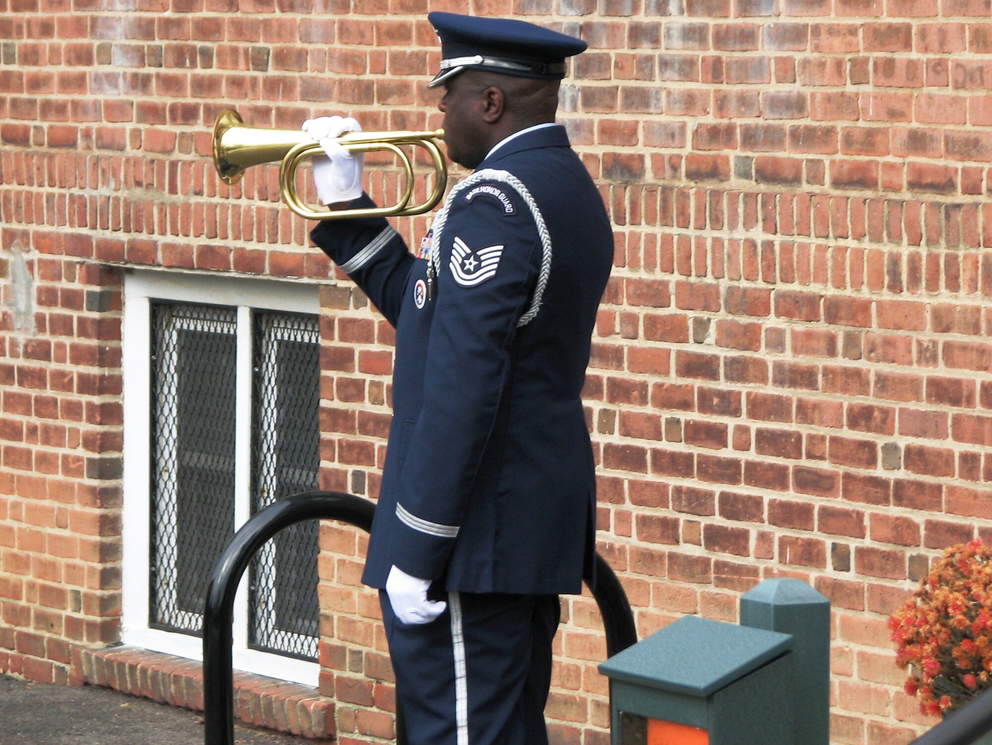 Technical Sergeant Richard Byrd, 439th Airlift Wing honor guard, plays taps while the U.S. flag is lowered from half staff during a Veteran's Day ceremony in Sunderland, Mass.