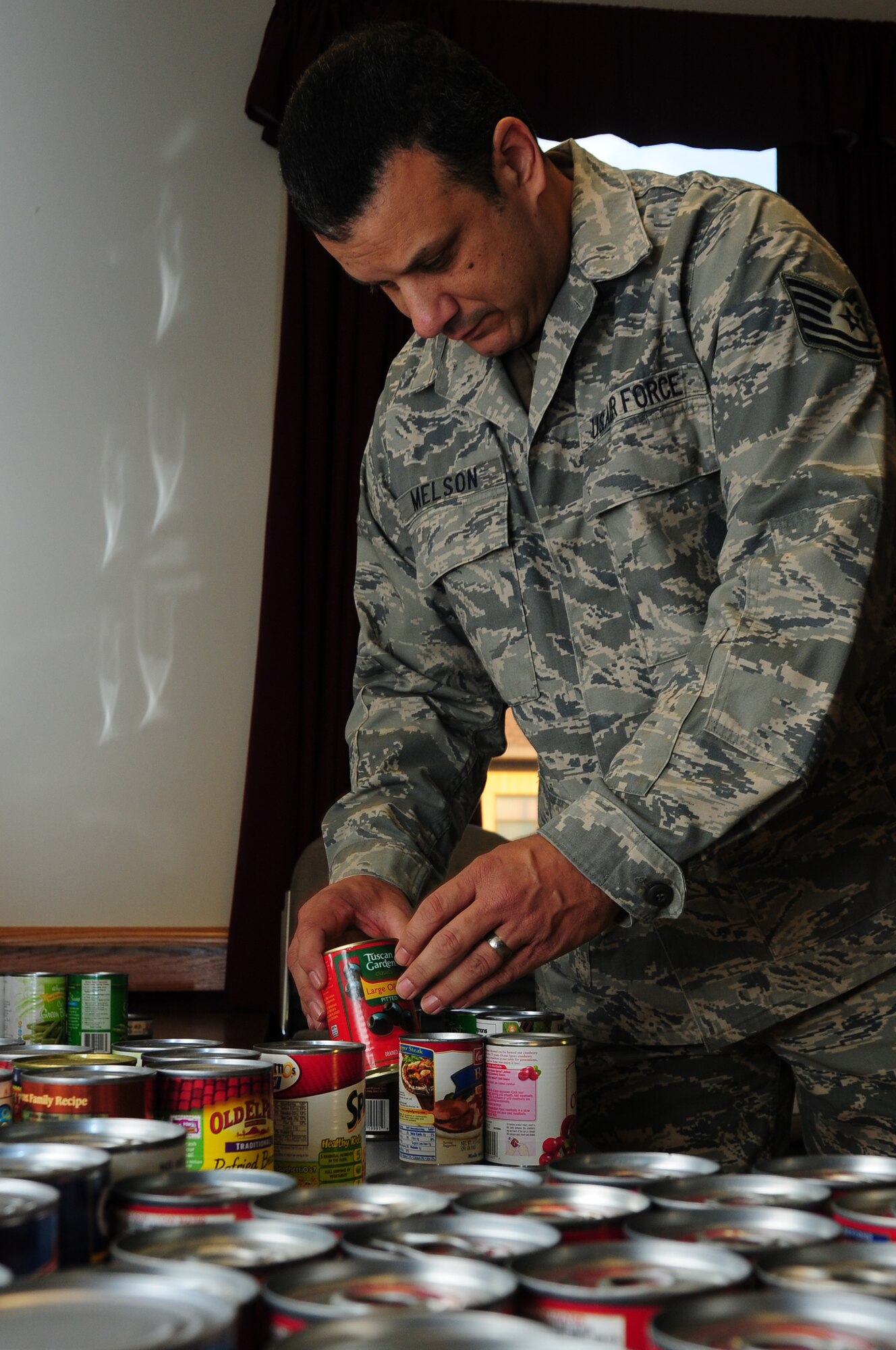 Tech. Sgt Michael Melson, 914th  Airman and Family Readiness  technician, places canned foods on a table in the base chapel annex.  Members from the 107th and 914th Airlift Wings donated food, gift cards and  toys for families in need during the holiday season.  Donations made to individuals are kept confidential.   The hours of operation are very flexible and the staff is friendly and willing to help in any way that they can.  (U.S. Air Force photo by Senior Airman Jessica Mae Snow)