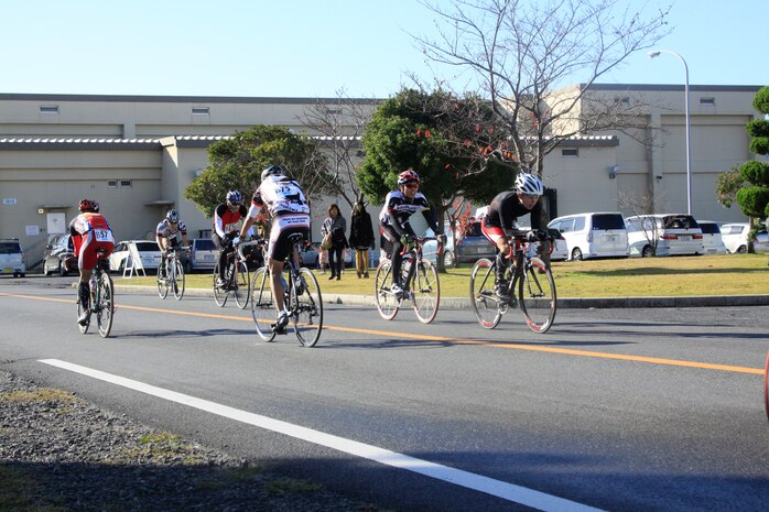 Athletes pass IronWorks Gym here during their bike route for the 2011 Heat the Streets Duathlon that took::r::::n::place here Sunday. Participants were spread out across the grass in front of IronWorks Sunday morning before the::r::::n::race started, stretching out to prepare for the challenge ahead. The Duathlon is an annual event sponsored by::r::::n::Marine Corps Community Services Iwakuni to strengthen bonds between station residents and Japanese locals.::r::::n::Besides Friendship Day, the races MCCS Iwakuni sponsors are the best way to allow locals access to the station. Participants started the race in front of IronWorks Gym with a four kilometer run to Penny Lake fields::r::::n::and back on the seawall. Participants then changed over to their bikes inside the bike rack area for a 24-kilometer::r::::n::biking portion. The last part of the race had participants place their bikes back in the racks and run for another four kilometers from the seawall to Penny Lake fields, finishing::r::::n::in front of IronWorks.
